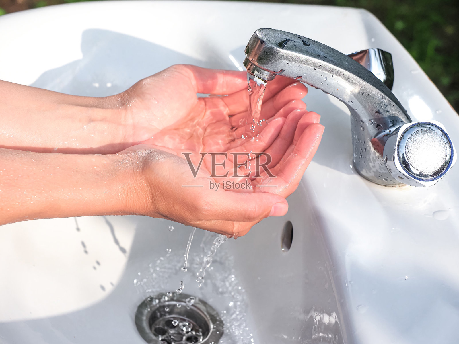 一个孩子正在家里浴室的水槽里用肥皂洗手。清洁、卫生和预防。前视图。照片摄影图片