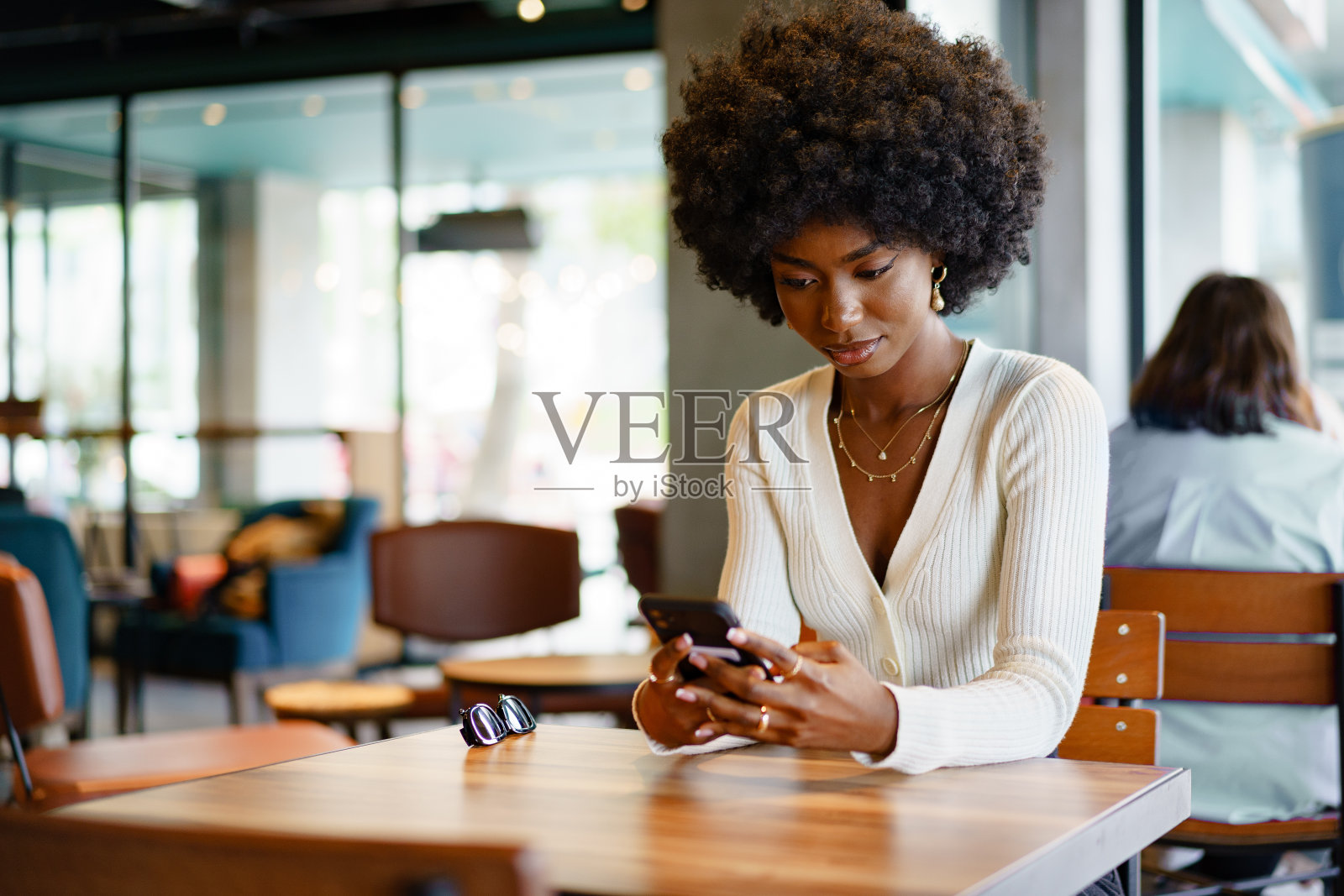 年轻的非洲女人在咖啡店用手机照片摄影图片