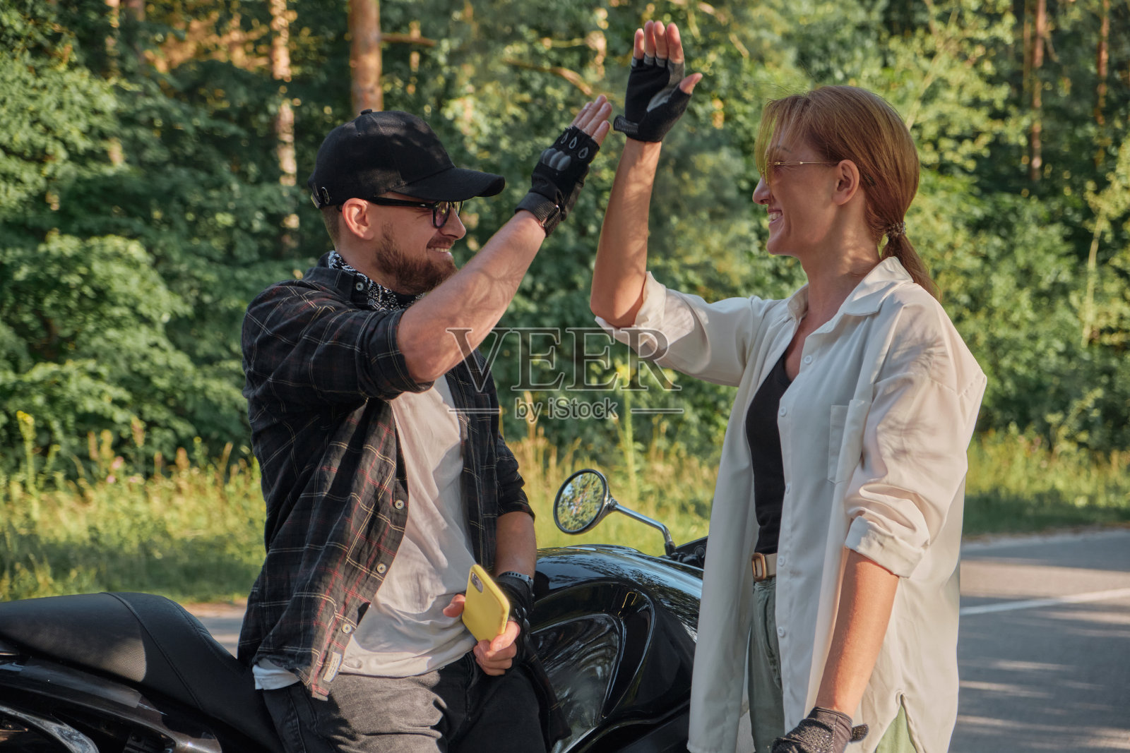 一对中年夫妇聊天,击掌,坐在摩托车上,一起在森林的路上旅行照片摄影图片
