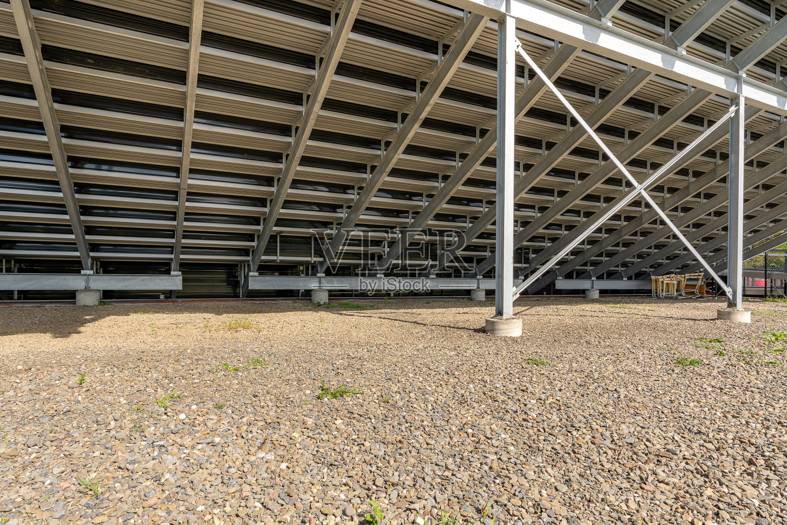 直接在体育场看台下的观点,偷I-Beam看台与X交叉支撑,与石头表面。照片摄影图片