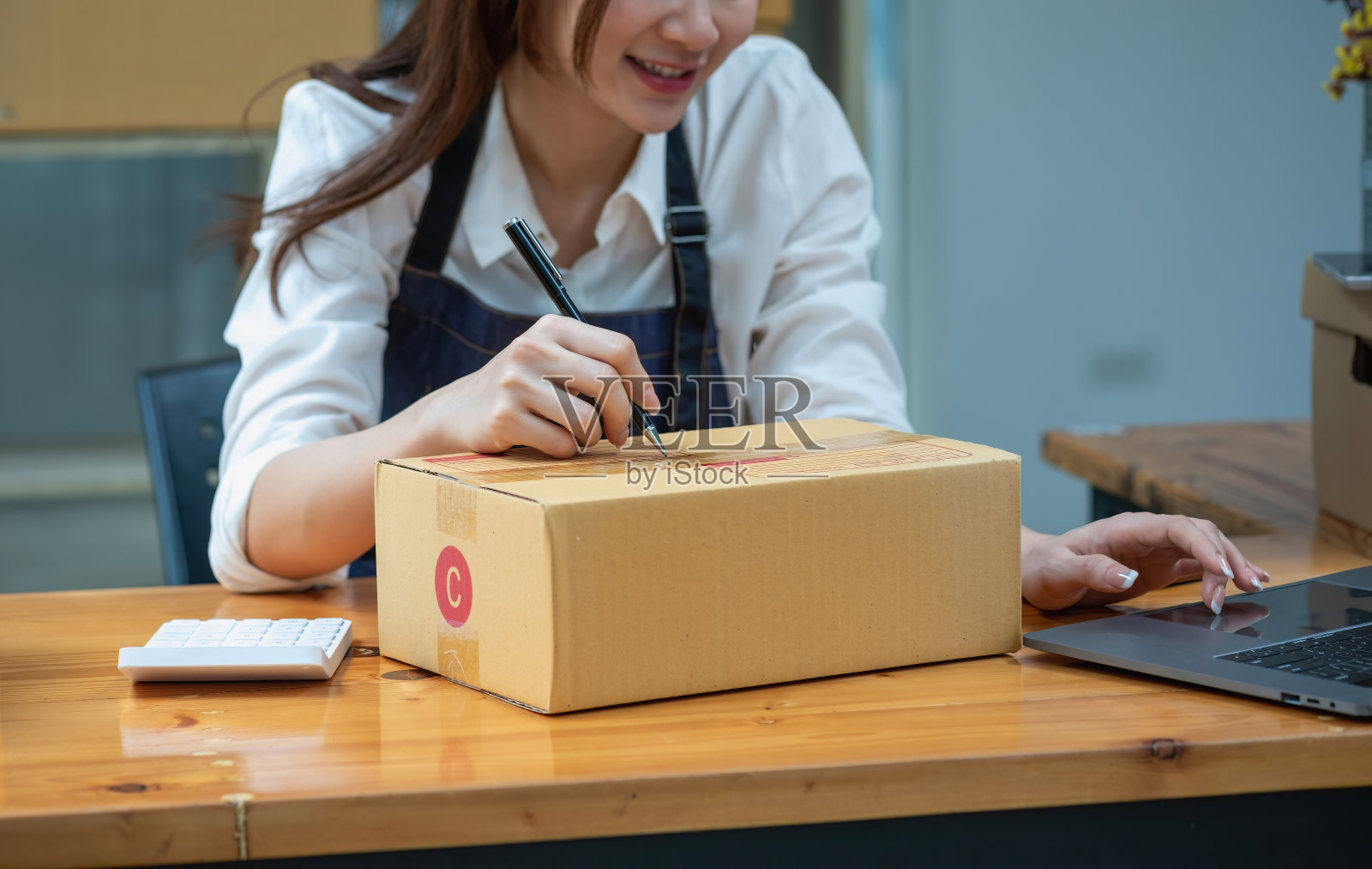 在线销售女企业主接收订单,并将产品与盒子运送给客户。网上中小企业经营理念。照片摄影图片