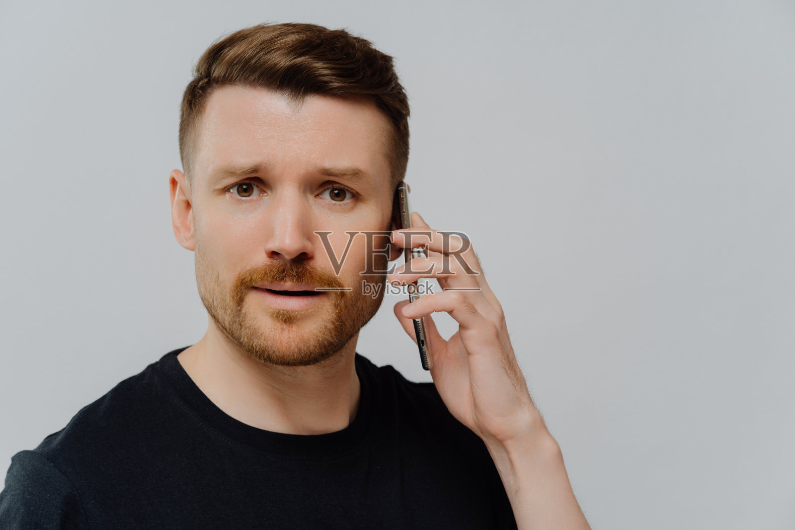 忧心忡忡的男人用手机进行不愉快的交谈,感到不开心照片摄影图片