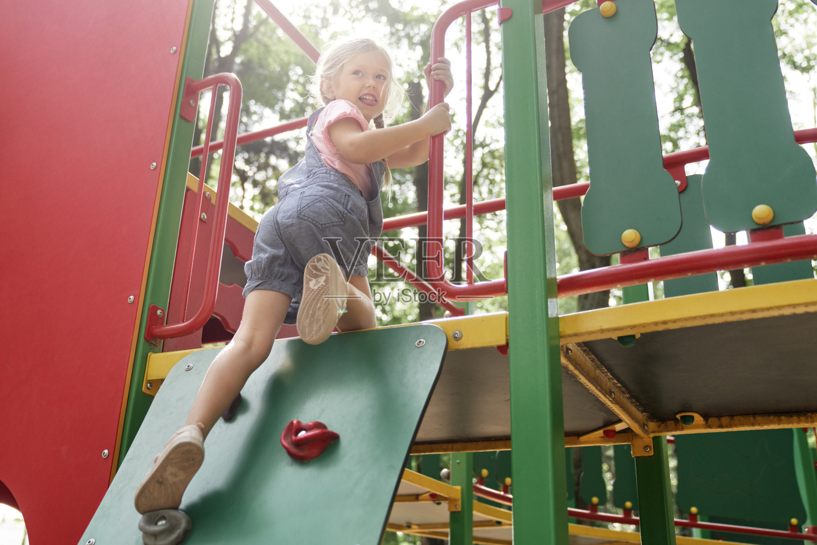 夏日,微笑的小女孩在操场上攀爬照片摄影图片