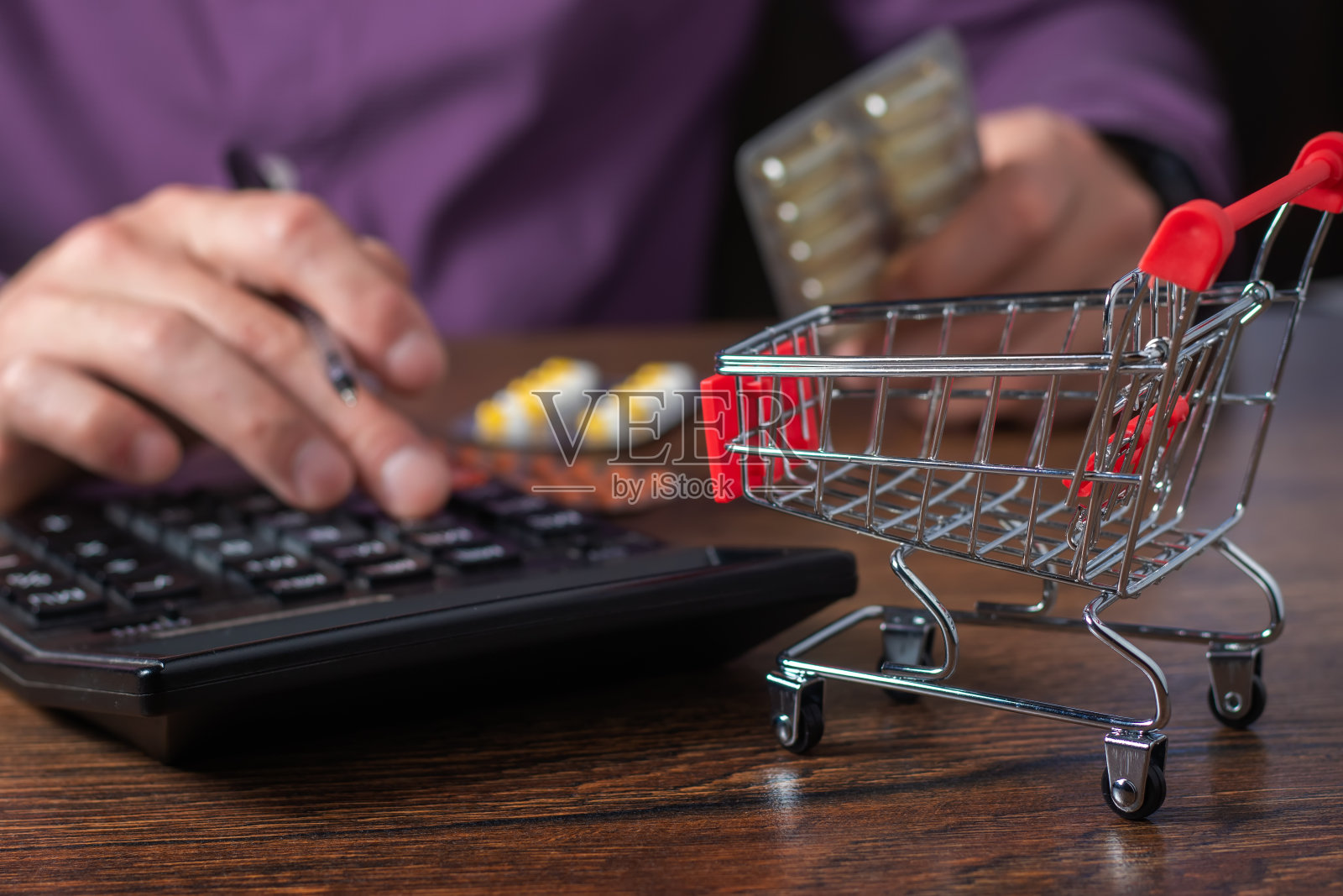 大额药品支出的概念。清空购物车。一个人用计算器计算药费。照片摄影图片