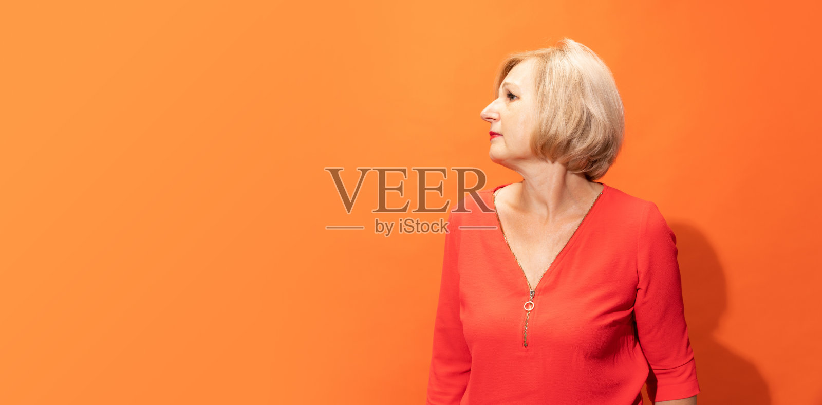 传单与肖像的美丽中年妇女与金发摆孤立的橙色背景。情绪的概念,面部表情照片摄影图片