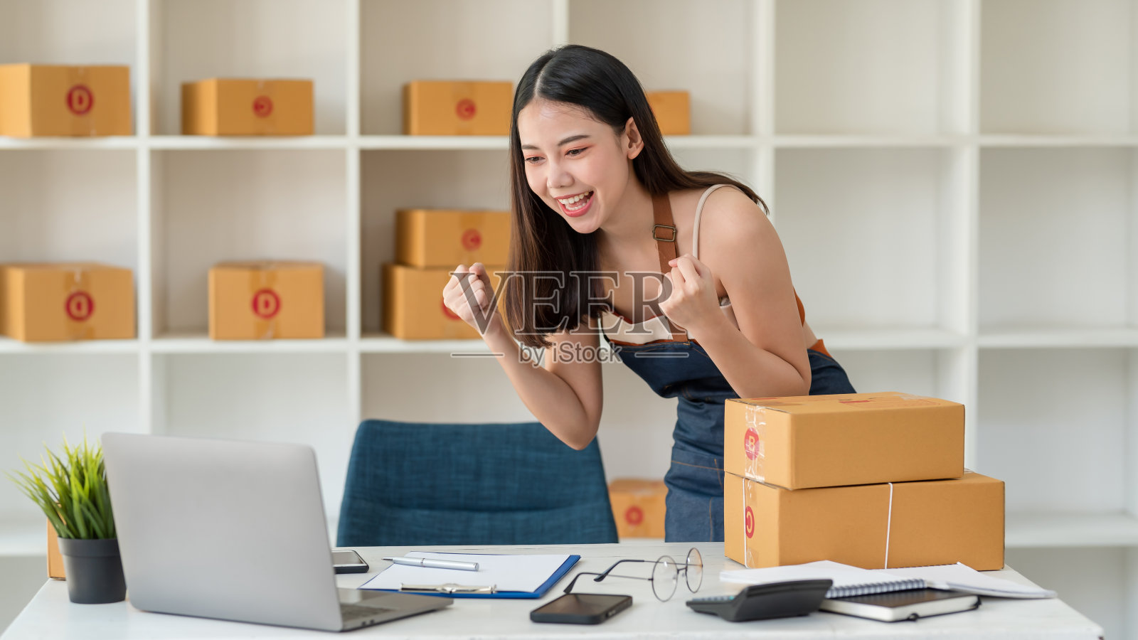 年轻的亚洲小企业主成功地使用笔记本电脑在网上销售。幸福的亚洲女商人成功兴奋的举起手来欣喜。照片摄影图片