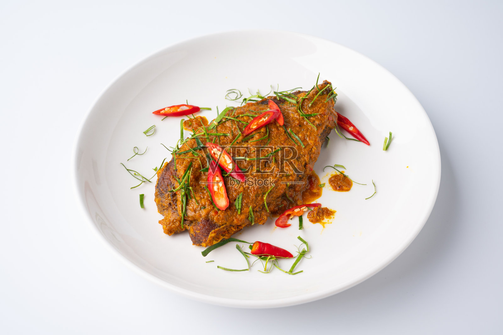 白盘子上的香辣红咖喱香脆炸鱼的近景照片摄影图片