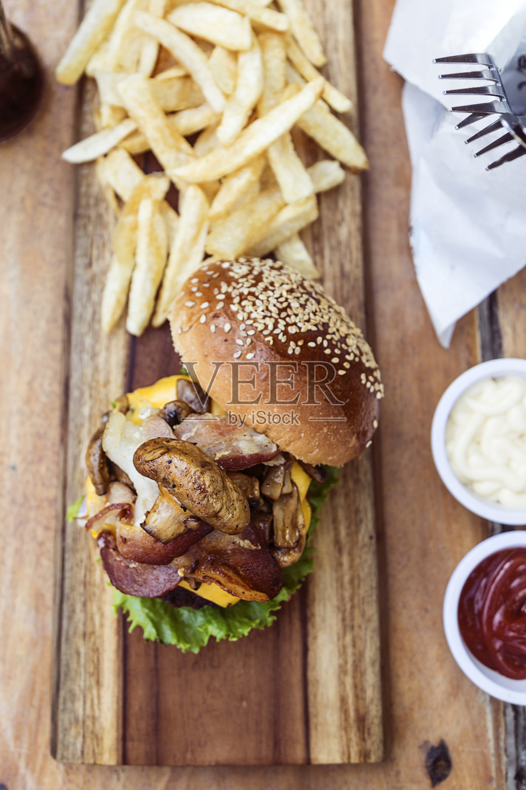 芝士汉堡配蘑菇,生菜,番茄,切达奶酪和培根,还有薯条照片摄影图片