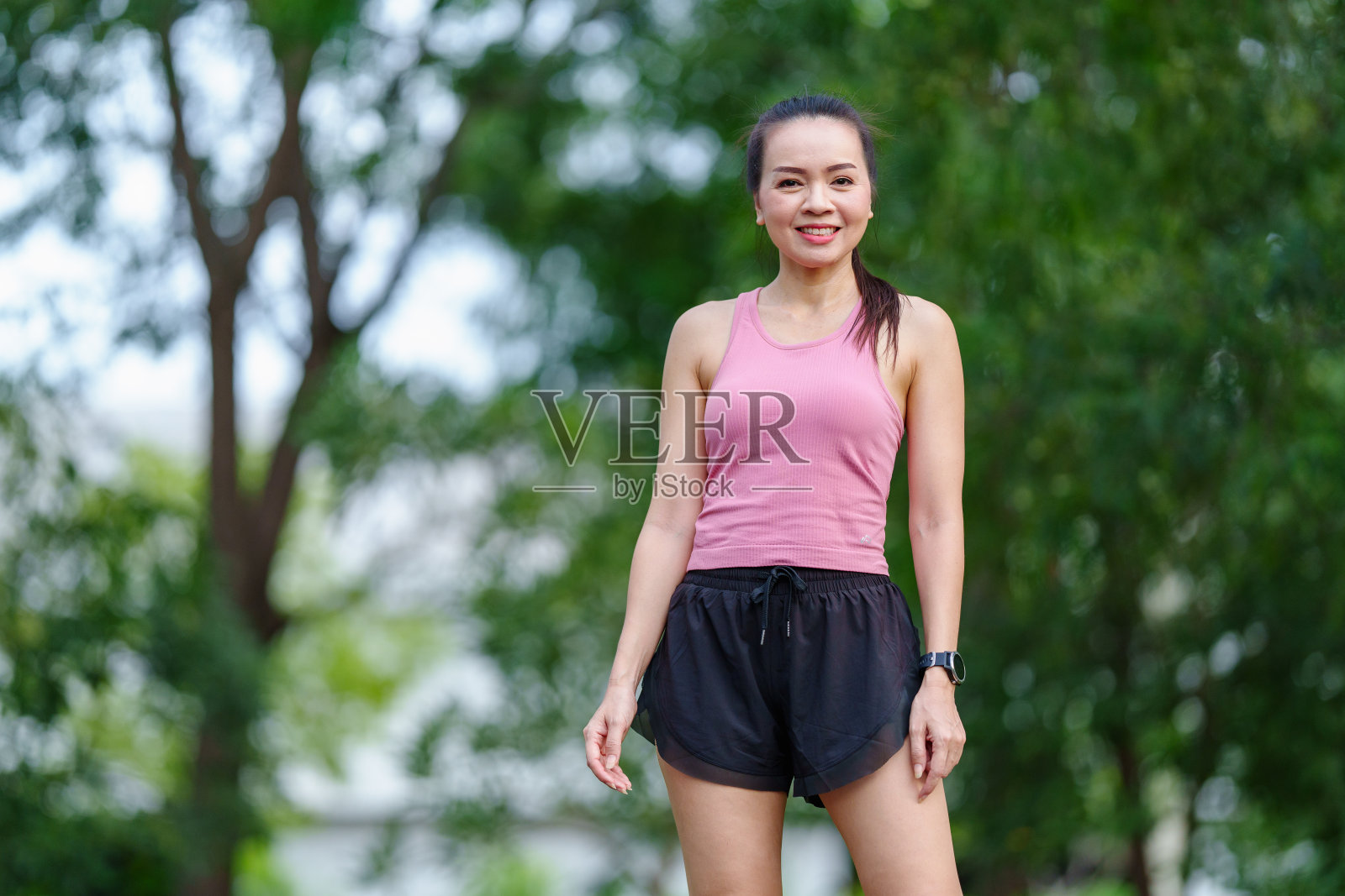 在健康的生活方式理念下,身穿户外服装的亚洲女性在城市自然公园慢跑前做伸展运动照片摄影图片