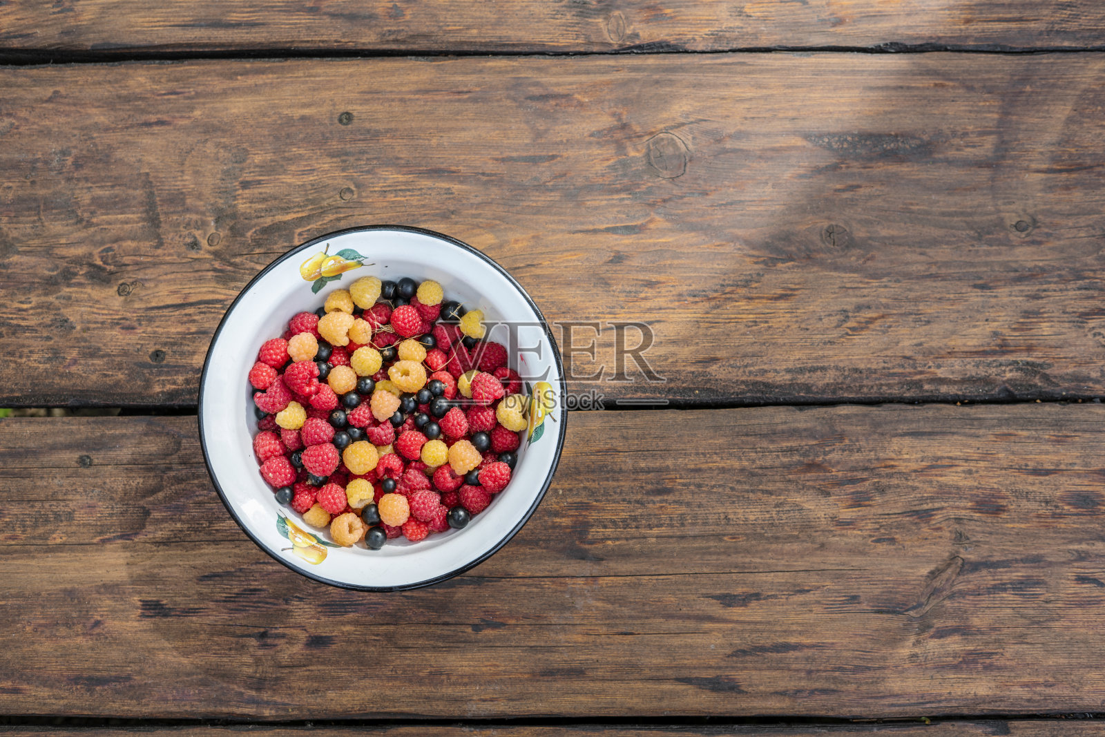一堆新鲜的树莓在碗上的木制背景。照片摄影图片