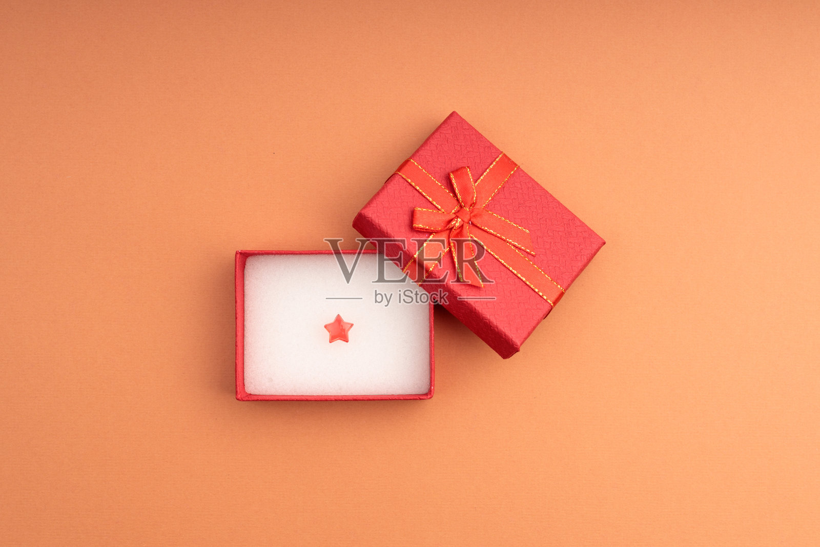 红色的塑料星星在一个打开的礼品盒,红色的盖子和红色的盒子照片摄影图片