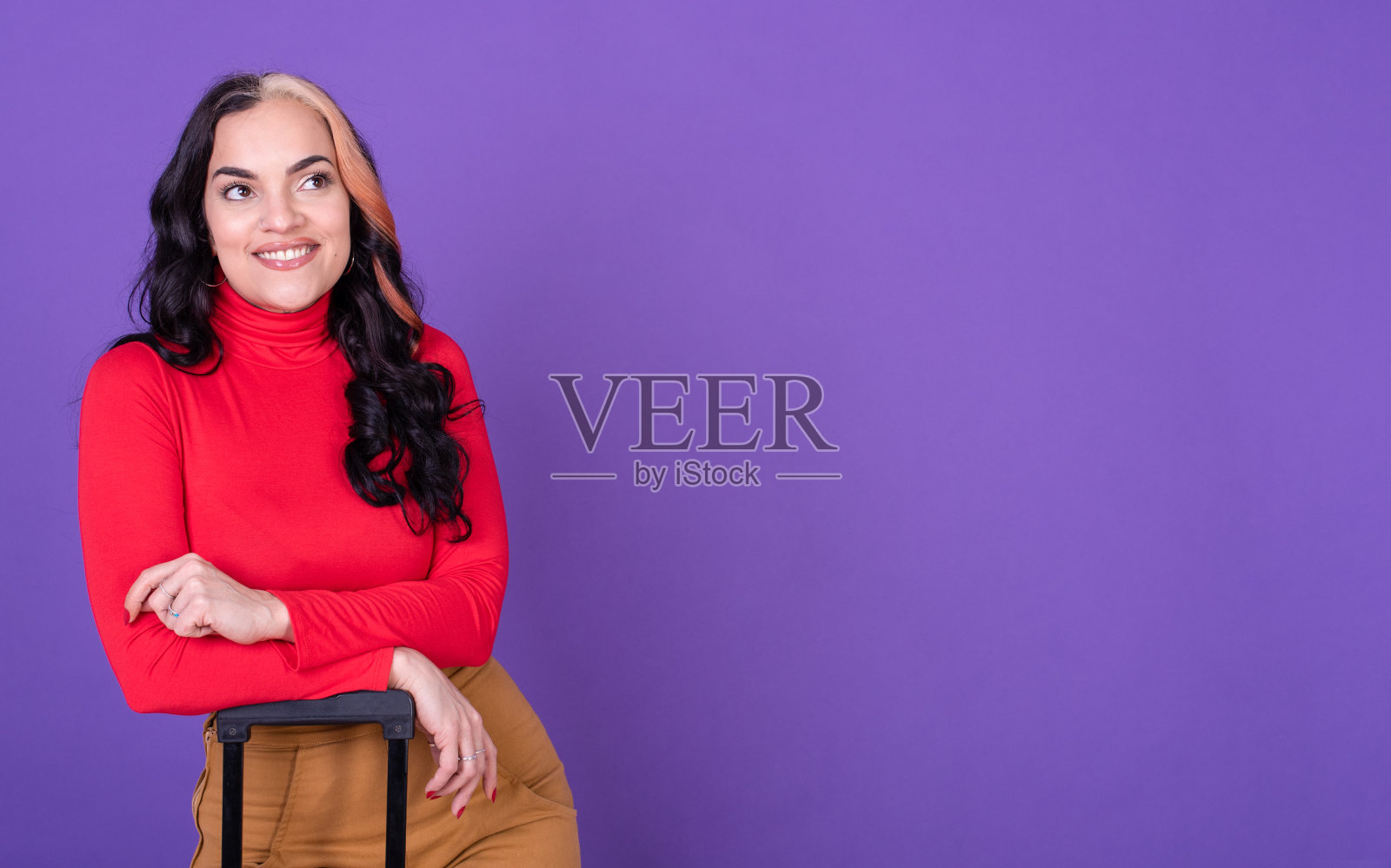 年轻快乐的女人旅行家手提箱对紫色的背景。副本的空间。照片摄影图片