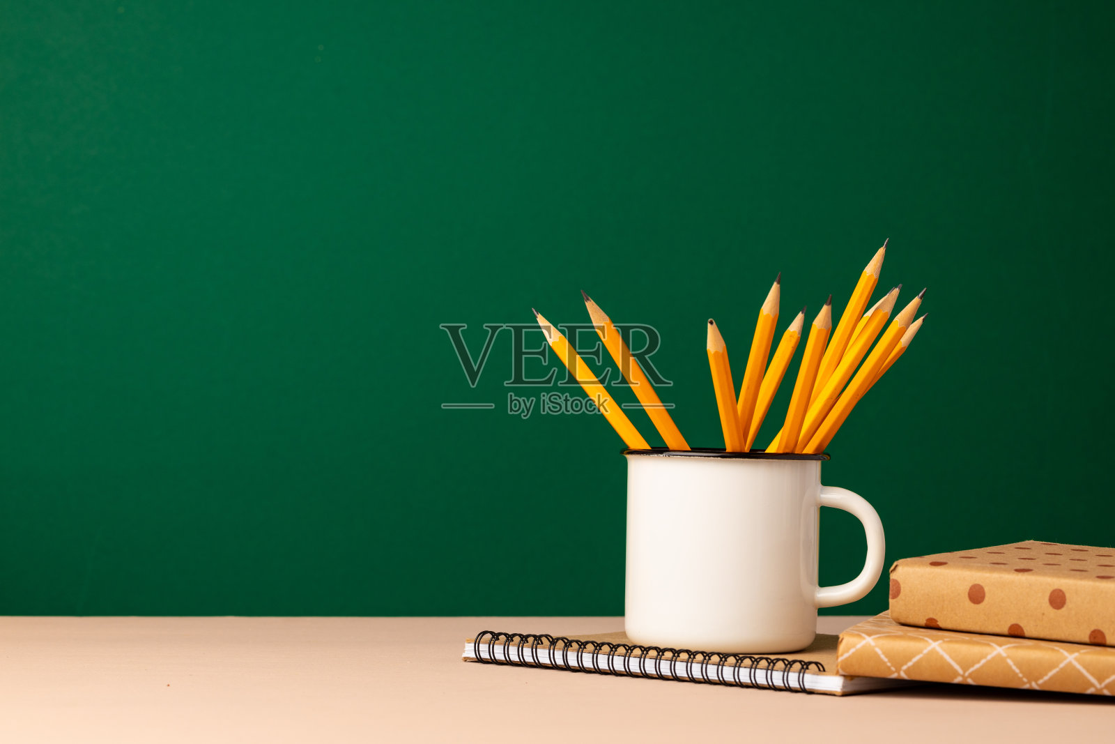 学校用品放在木制的桌子上,对面是绿色的黑板照片摄影图片