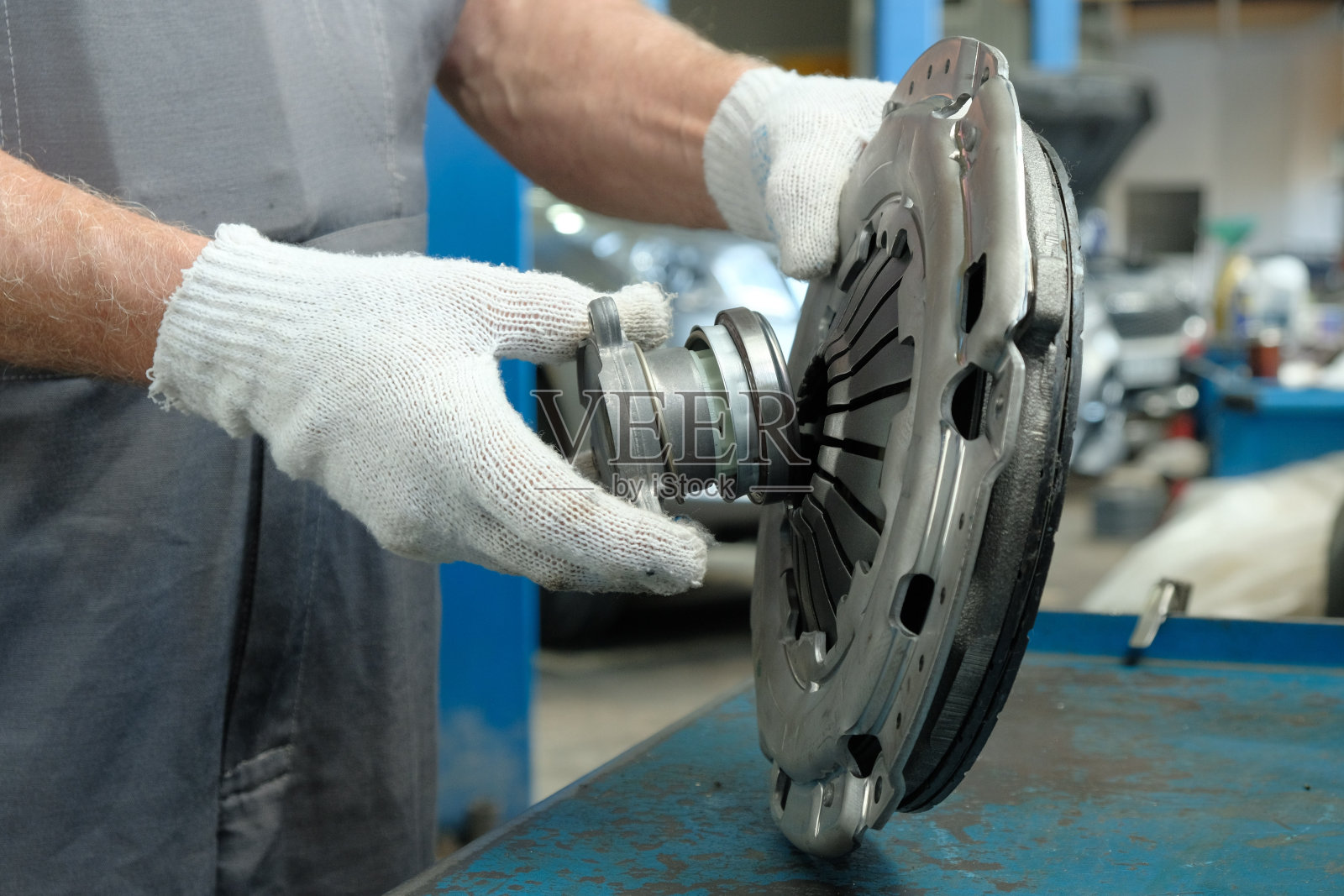 汽车修理工拿着离合器。汽车服务中心的维修和保养。照片摄影图片