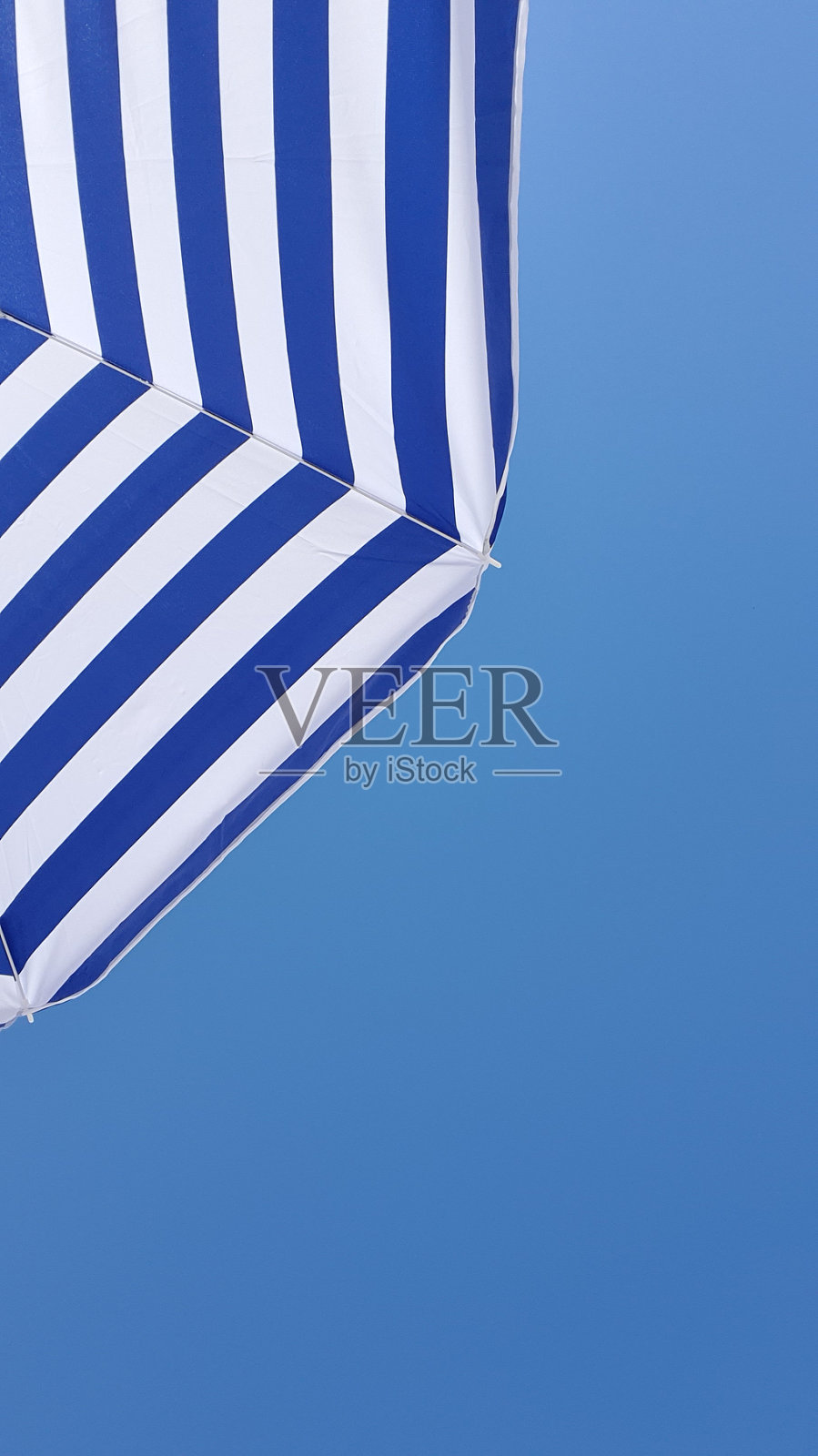 蓝色和白色的沙滩伞映衬着蓝色的天空照片摄影图片