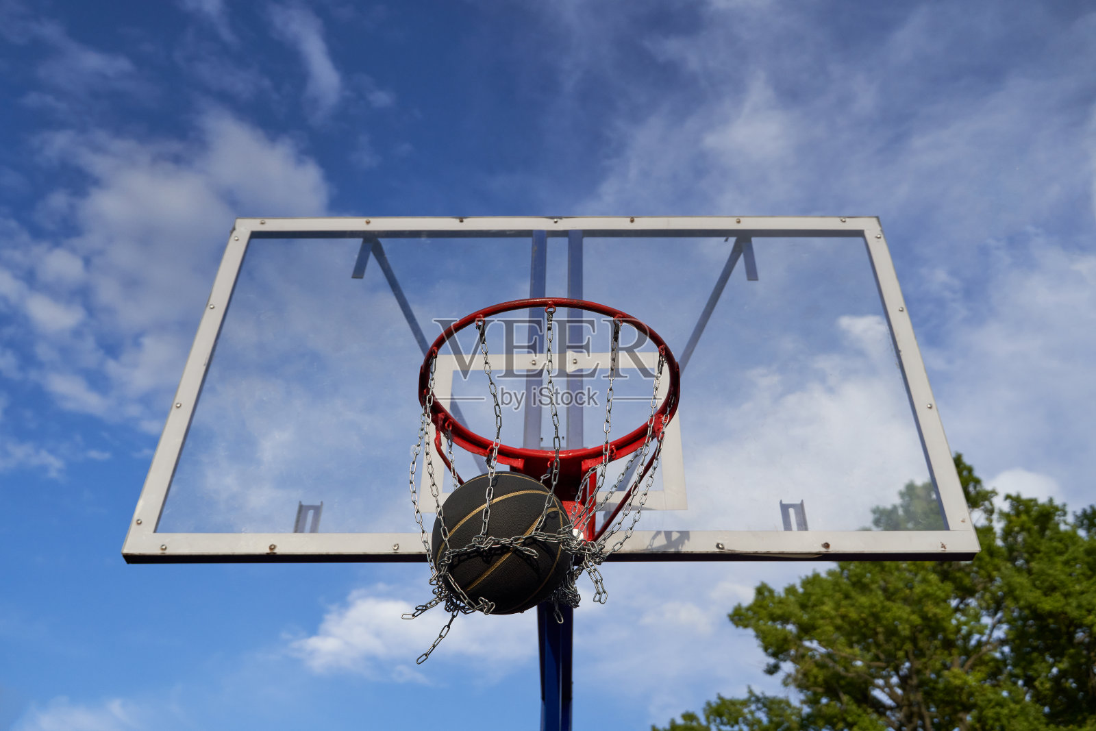 街头篮球落入篮筐。黑球在篮网中的特写。照片摄影图片