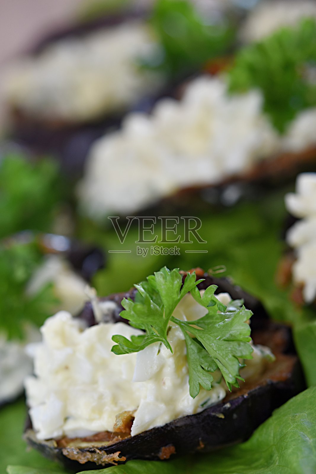 煎茄子开胃菜,夹有鸡蛋、芝士、大蒜和香草,配以欧芹和生菜照片摄影图片