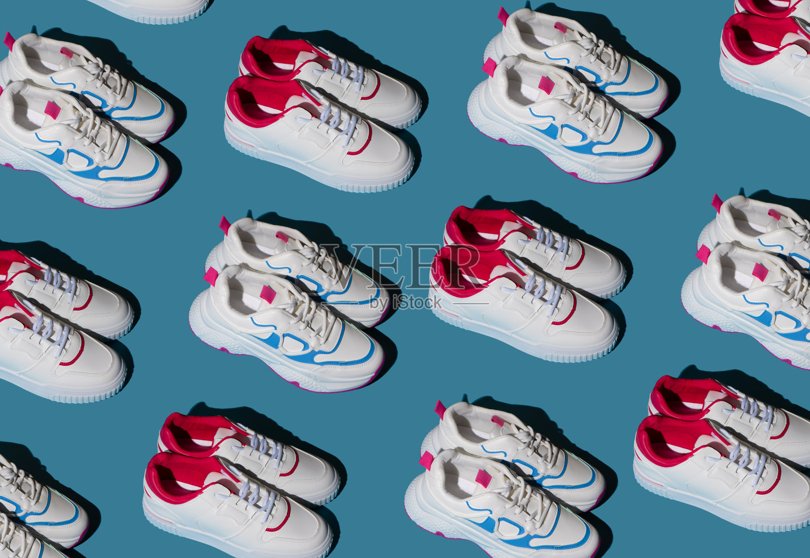 蓝色背景上白色运动鞋的图案。新运动鞋。一对休闲时尚配饰照片摄影图片