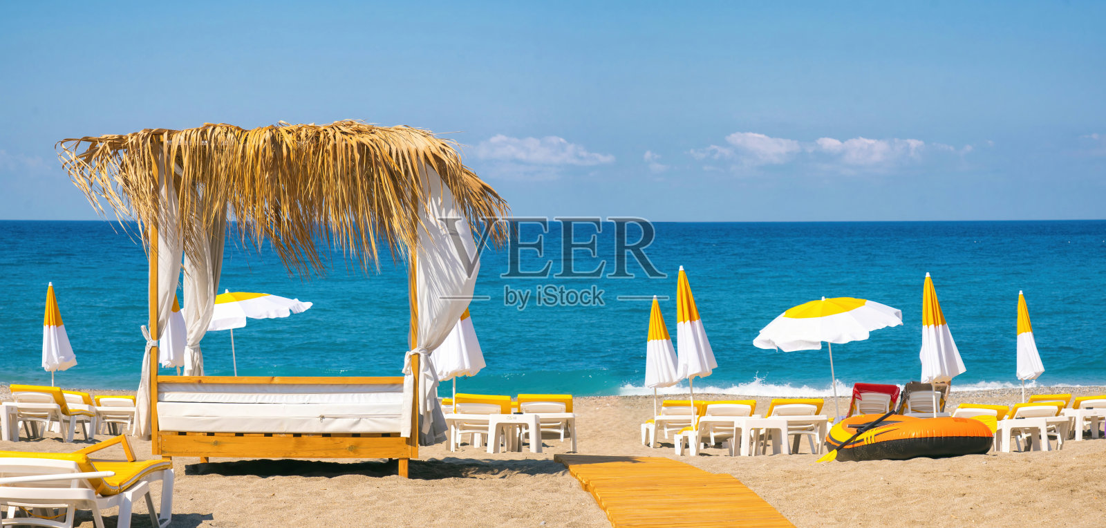 美丽的沙滩,黄色的沙子,蓝色的天空,广阔的蓝绿色的海洋,阳光躺椅和雨伞。照片摄影图片