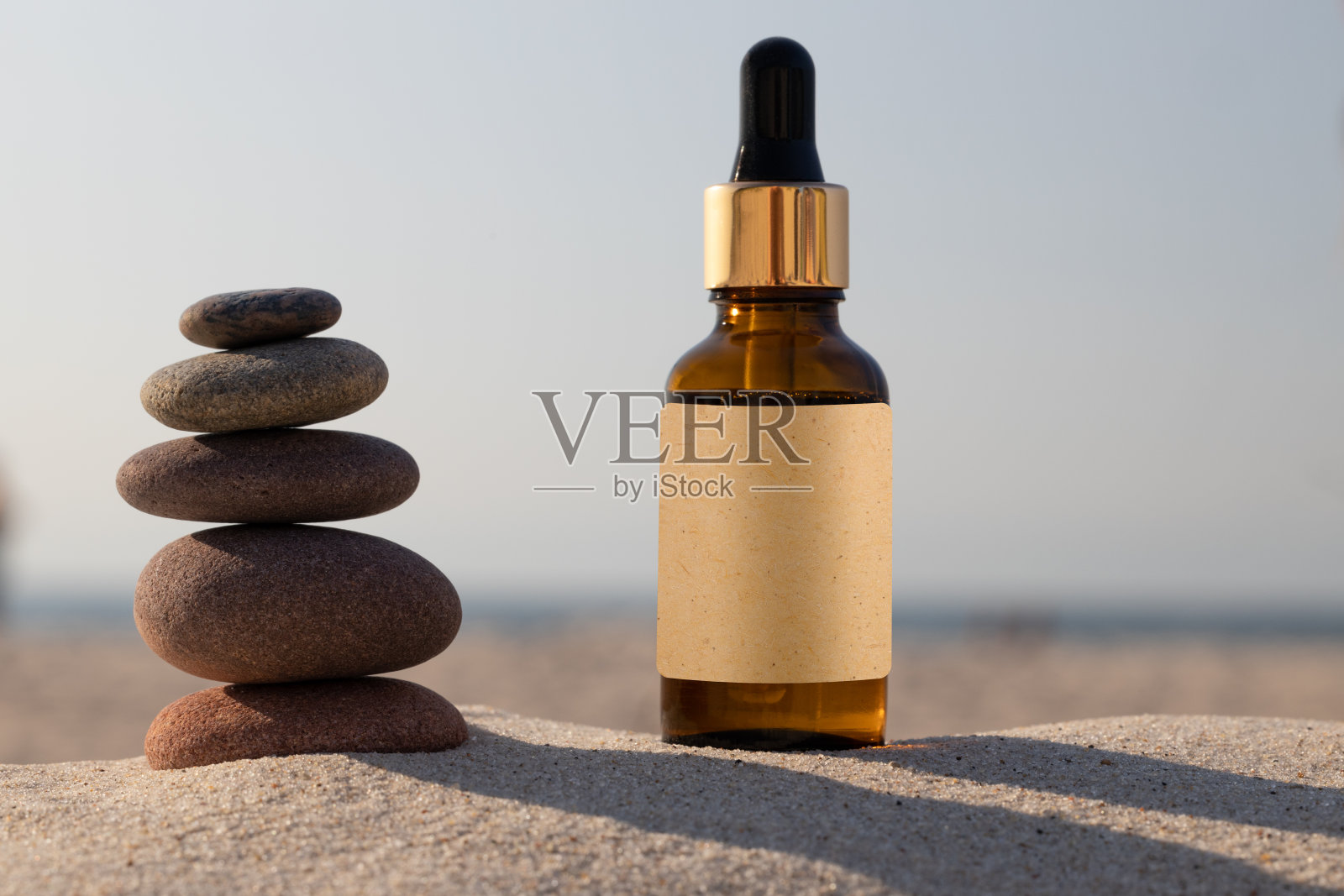 玻璃瓶,防晒油。天然草药油。金黄色的瓶子在沙滩上的沙子。模型,照片摄影图片