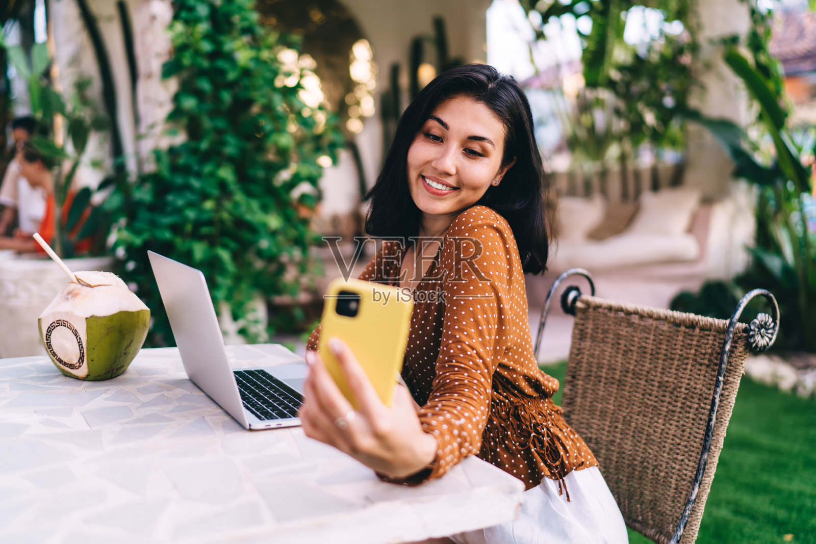 年轻漂亮的亚洲女人在街头自助餐厅用笔记本电脑用智能手机自拍照片摄影图片