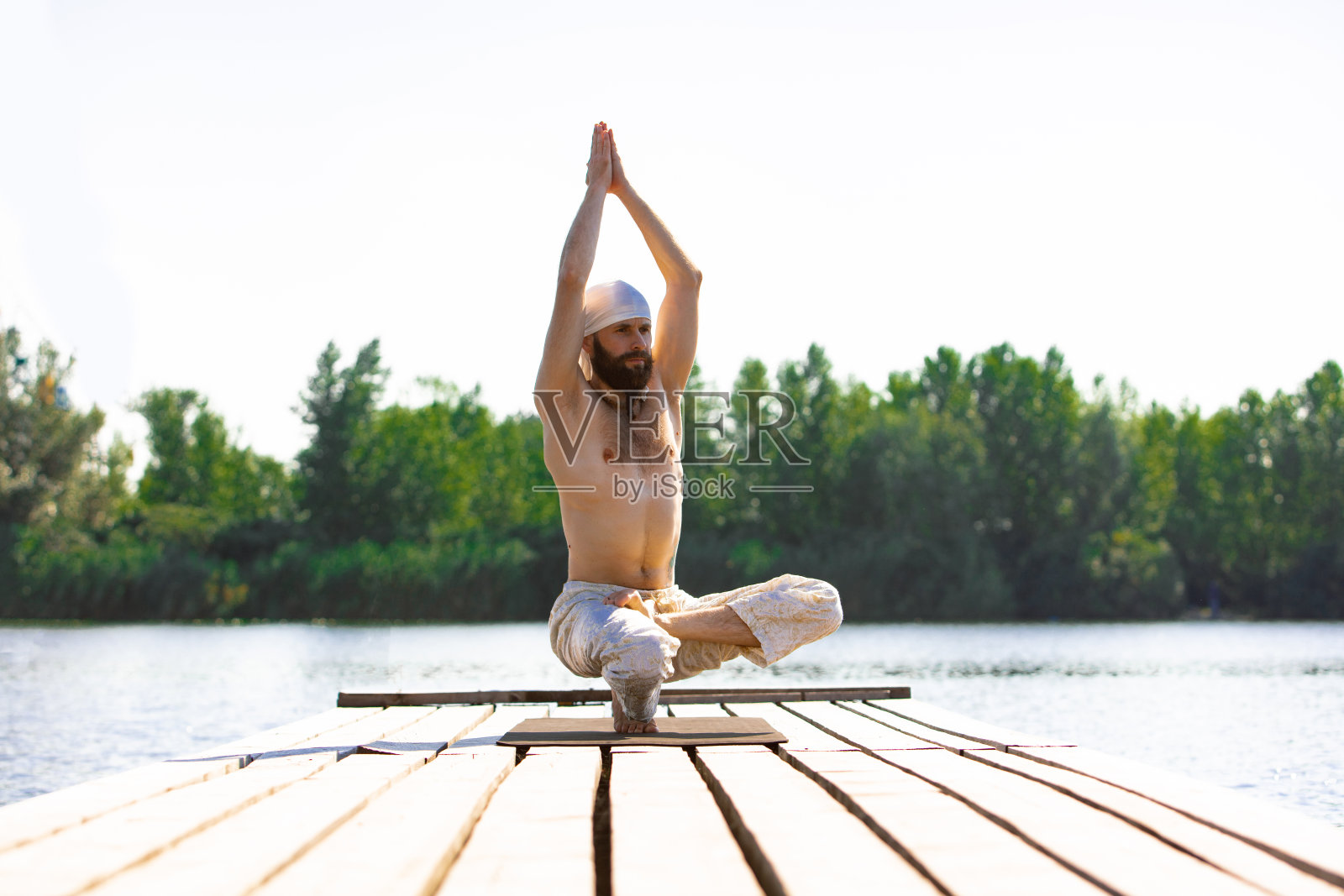日出时,在河边练习瑜伽的年轻男子照片摄影图片