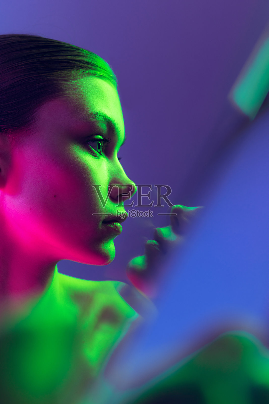 迷人的年轻,美丽的女孩保持良好的皮肤隔离在蓝色背景的霓虹灯。艺术、时尚、风格、表情照片摄影图片