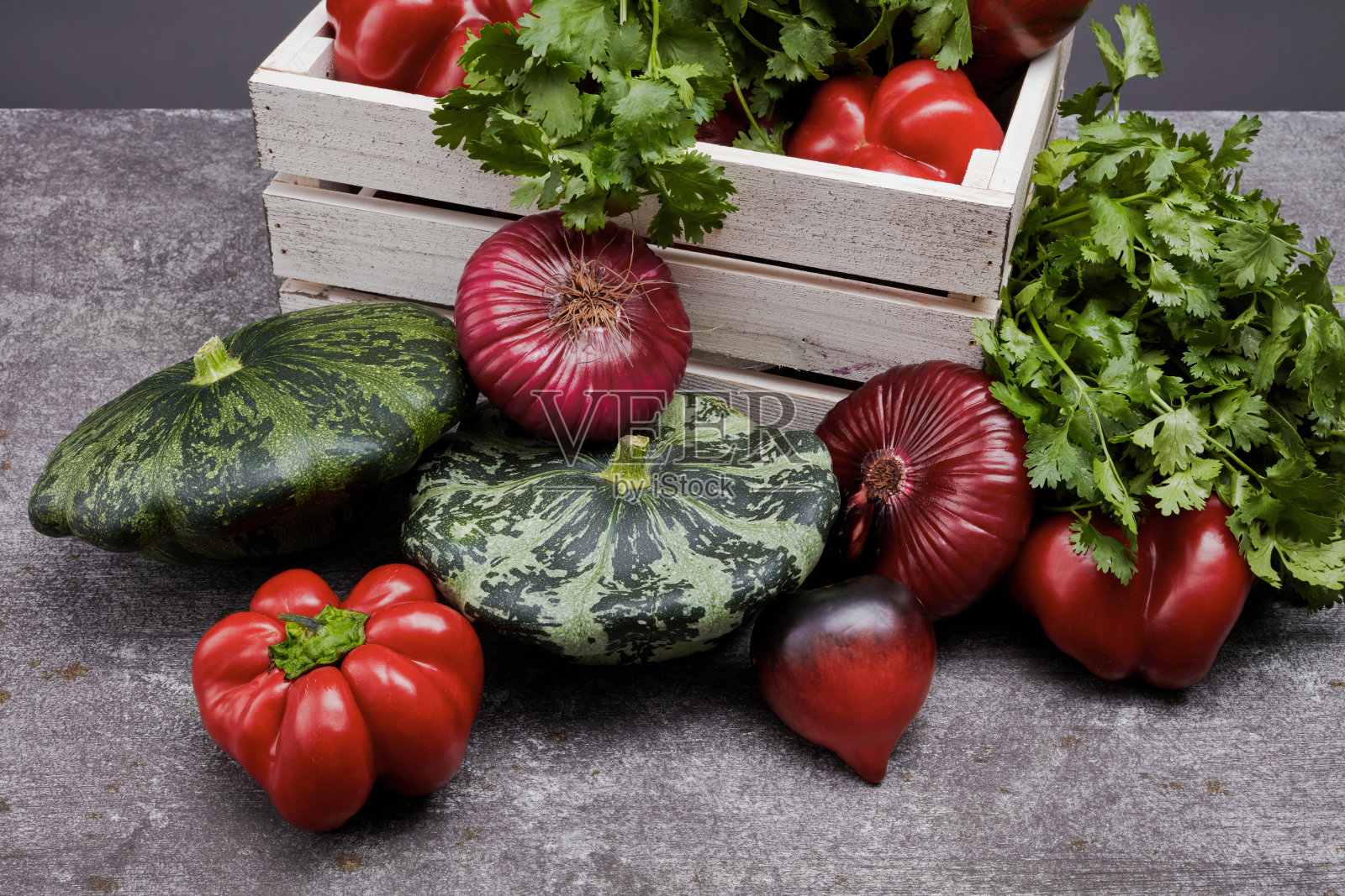 松木盒子里装满了五颜六色的新鲜蔬菜,摆在桌子上,灰色的背景。照片摄影图片