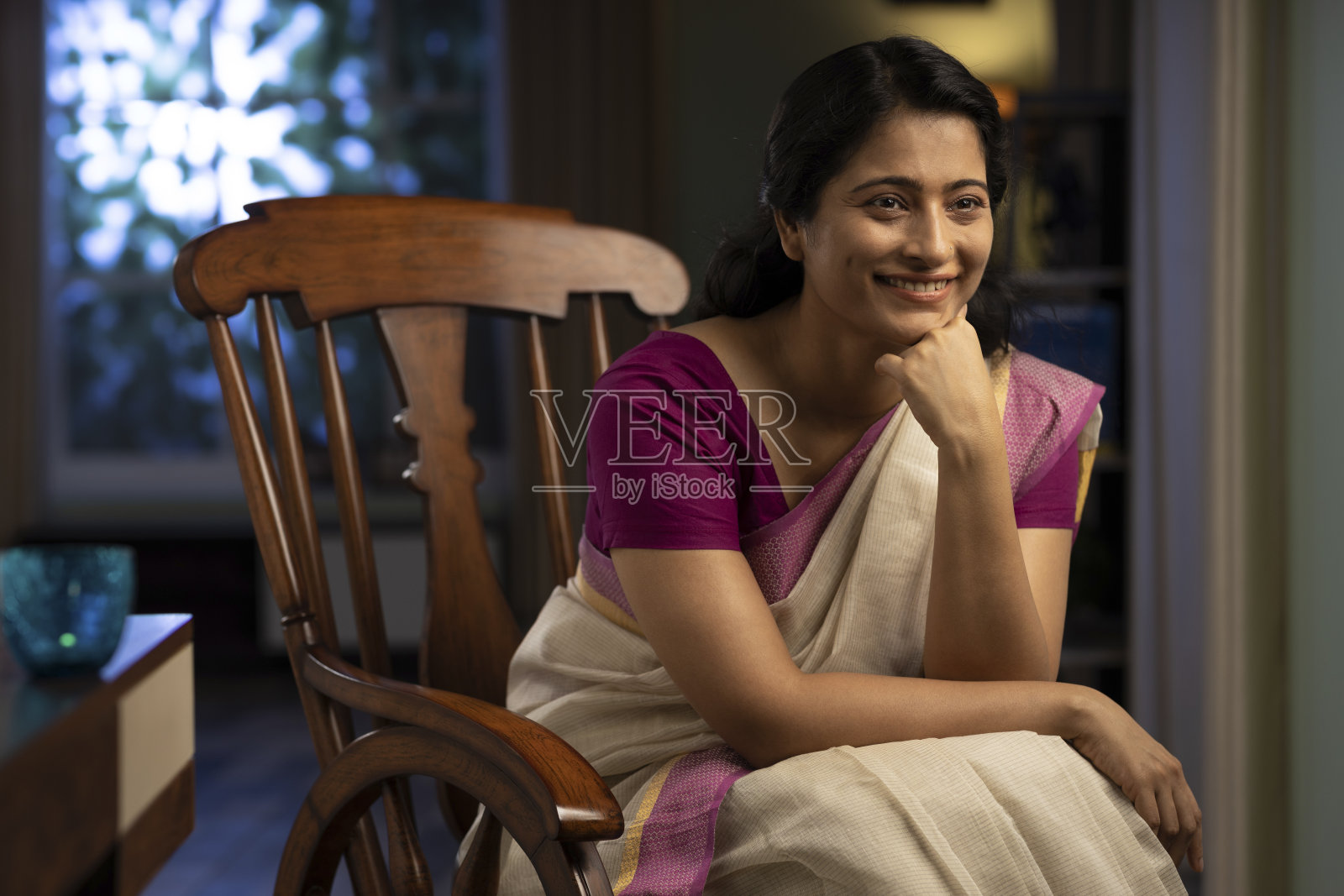 一个女人在纱丽坐在家里的摇椅上的拍摄,库存照片照片摄影图片