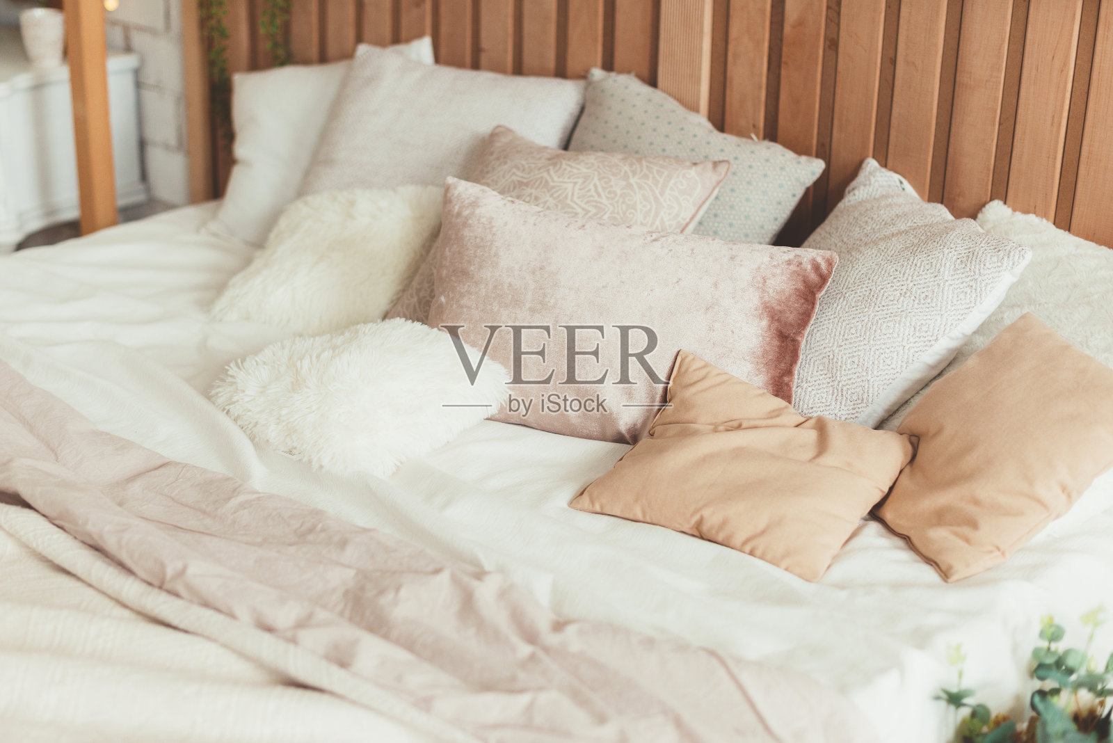 房间里的床上放很多颜色柔和的枕头,具有中性的审美照片摄影图片