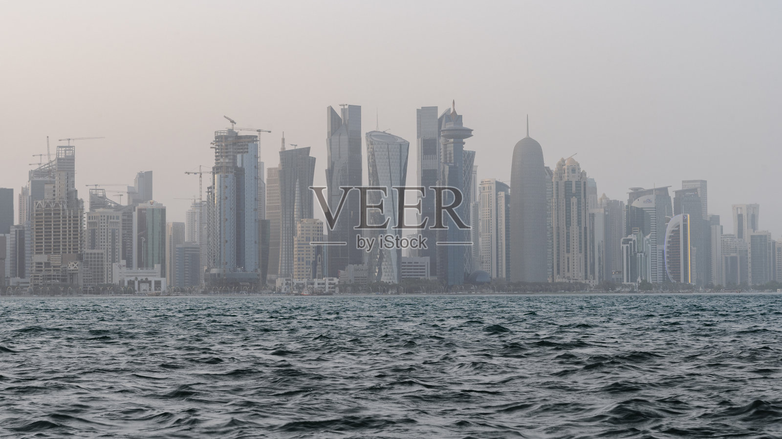 在刮风下雨的日子里,卡塔尔的天际线前景是波涛汹涌的大海。照片摄影图片