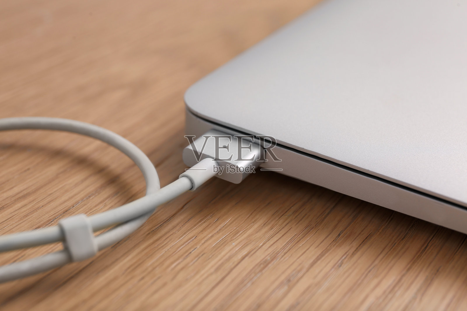 现代笔记本电脑和充电电缆放在木桌上,特写照片摄影图片