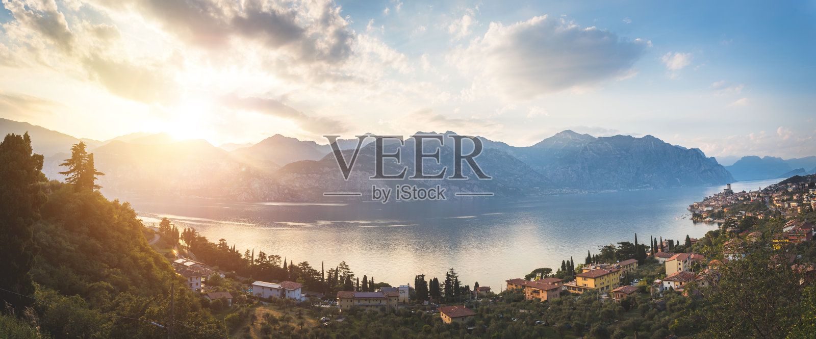 意大利田园诗般的海岸线:蓝色的海水和一个可爱的村庄在拉戈迪加尔达,马尔塞辛,日落照片摄影图片