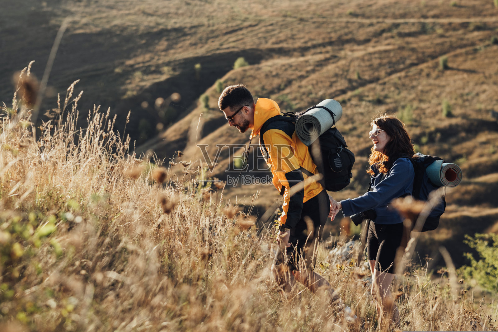 旅行夫妇男人和女人与背包和露营垫的手在山上移动在日落照片摄影图片
