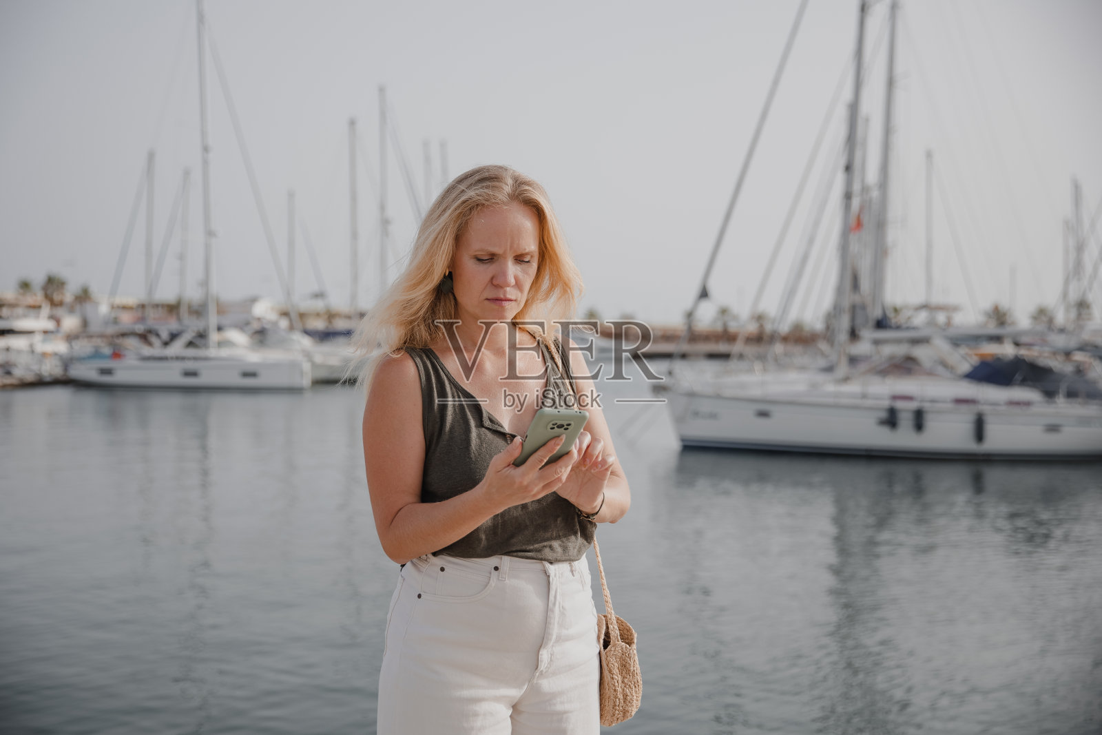 美丽的女人在蓝色的大海和游艇的背景下打电话照片摄影图片