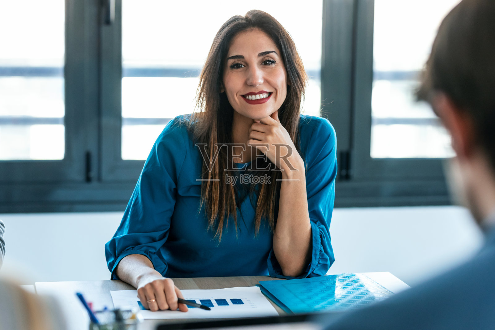 美丽的商务女性一边设计蓝图,一边在办公室和同事们谈论新项目。照片摄影图片