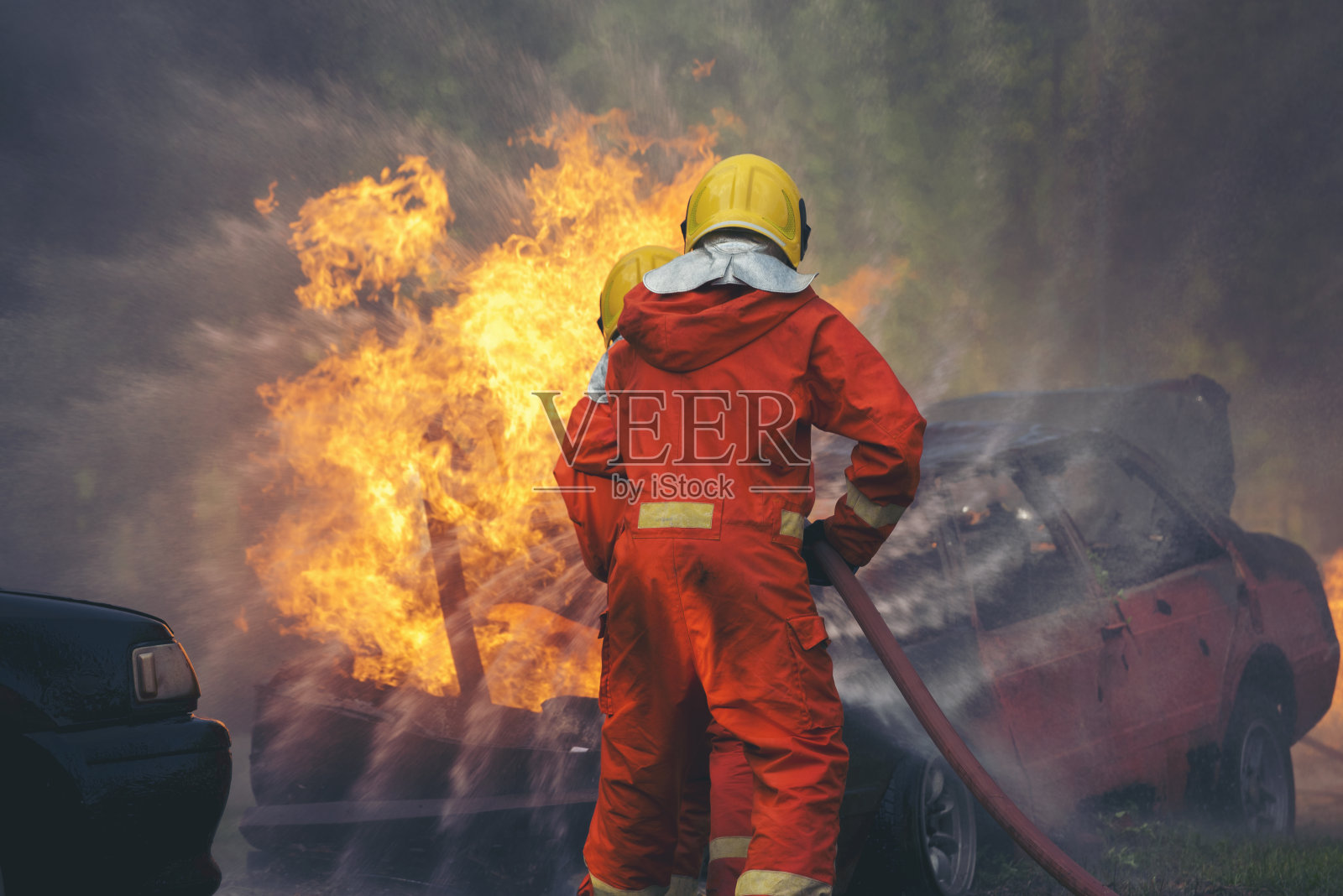 消防队员消防灭火器救援训练。消防队员使用消防软管化学水泡沫喷射发动机与火焰搏斗。消防队员戴安全帽,穿安全防护服照片摄影图片