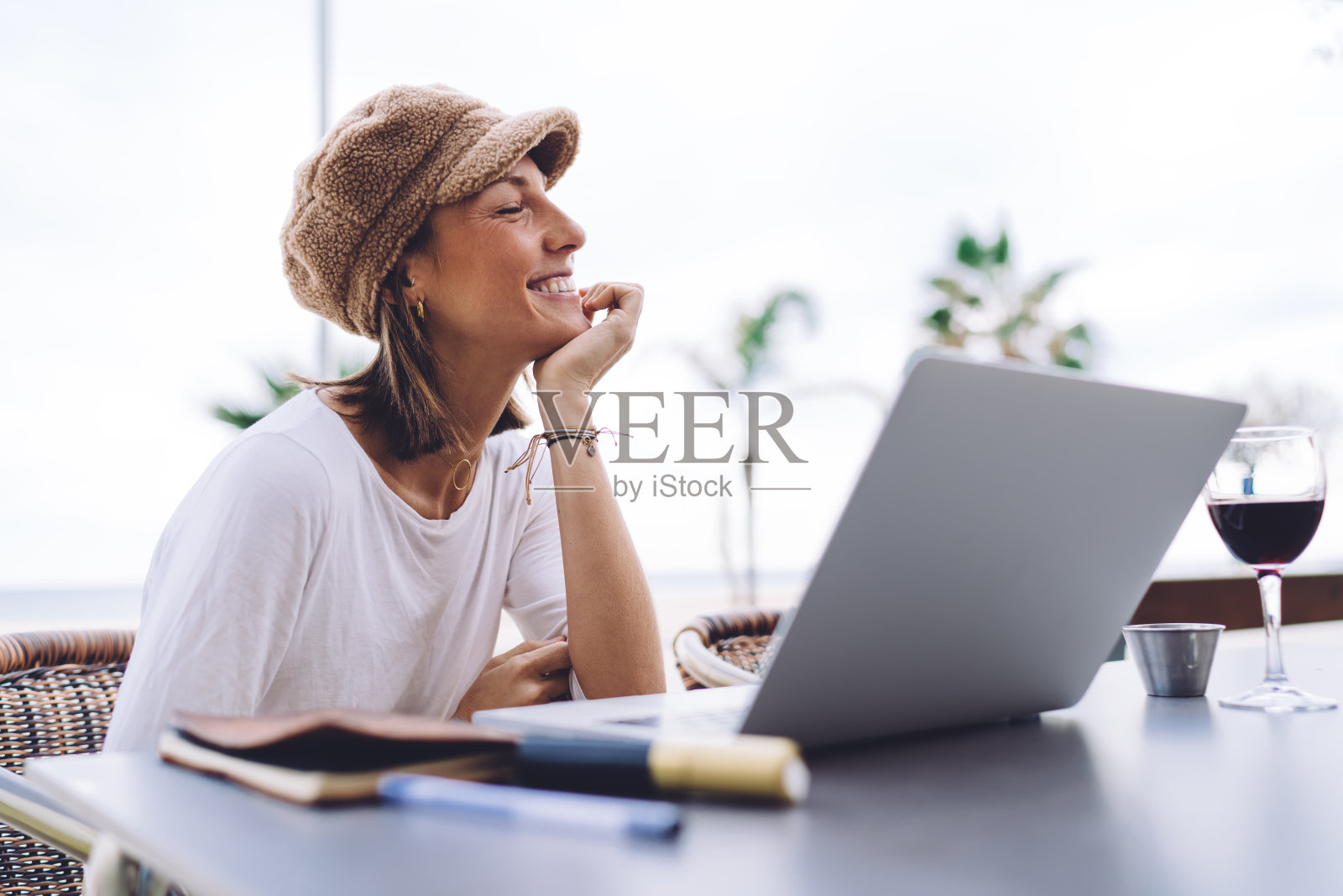 空闲时间利用无线网络在咖啡馆露台上观看视频的快乐白人女性,用笔记本电脑在网上搜索信息的微笑的20多岁女性照片摄影图片