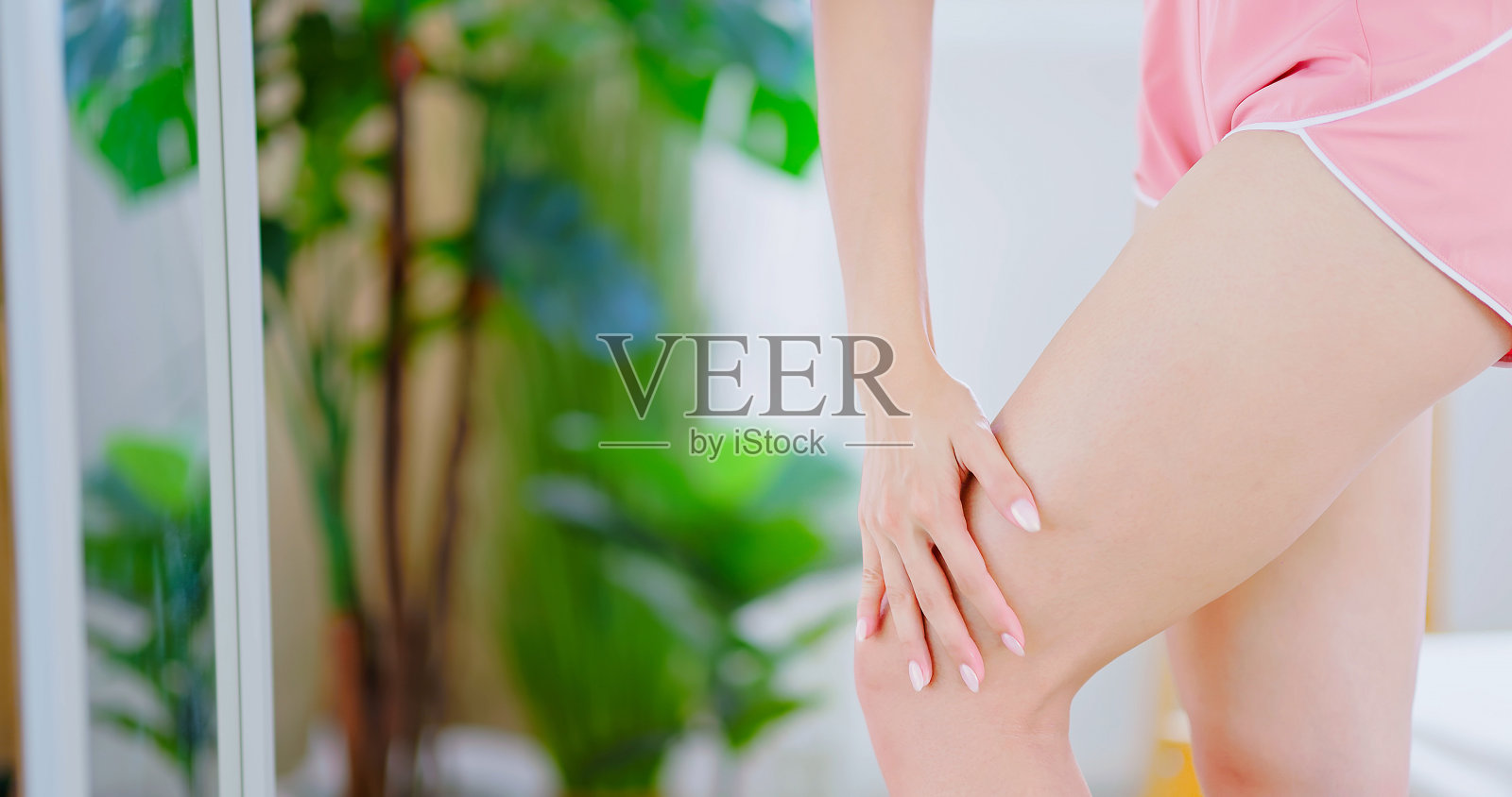 女孩在大腿上涂乳液照片摄影图片