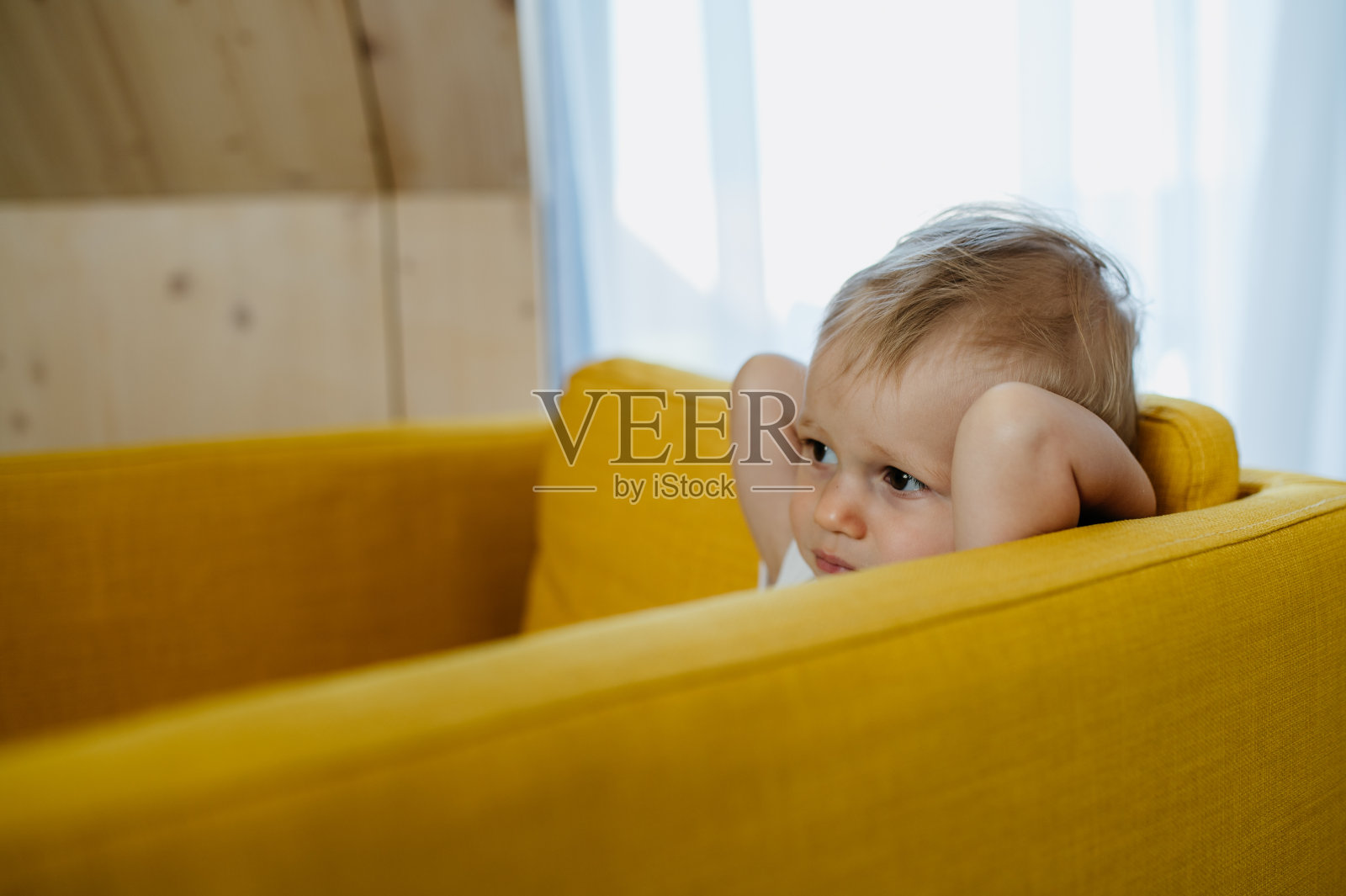 好奇的小女孩坐在沙发上,看向别处。照片摄影图片