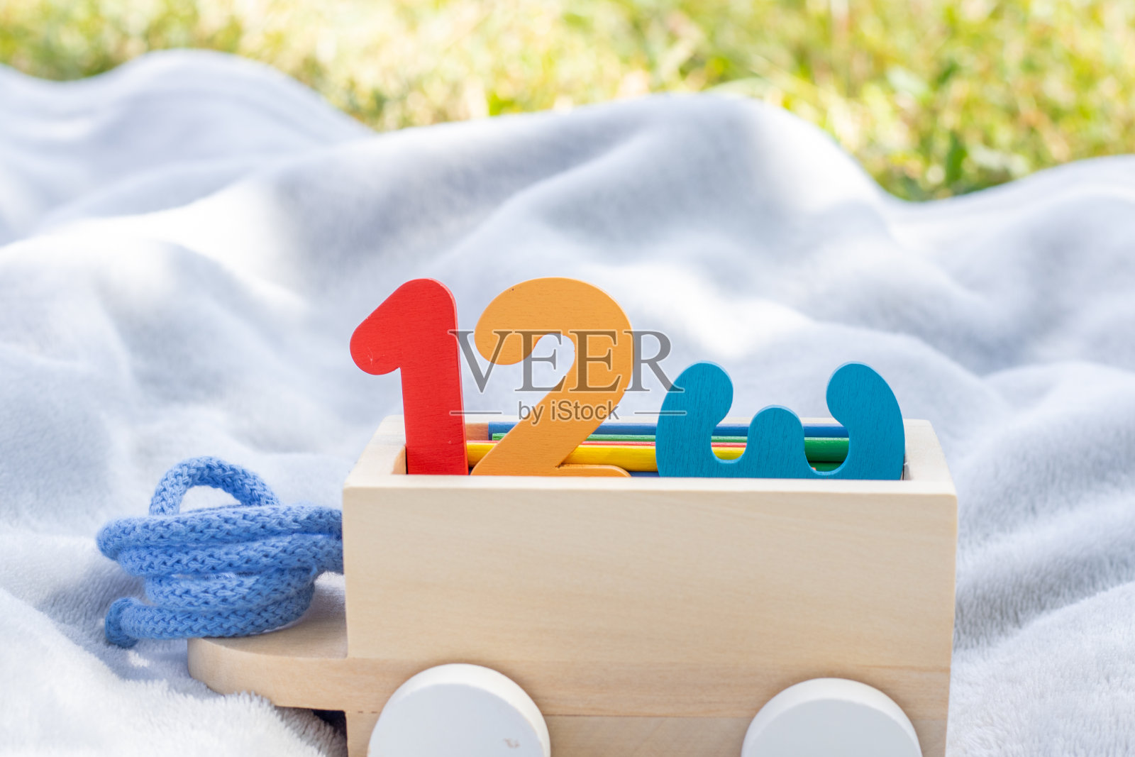 在毛毯上的玩具火车上学习木制数字和彩色计数棒。泡沫垫数字宝宝腿,阳光。回到学校照片摄影图片