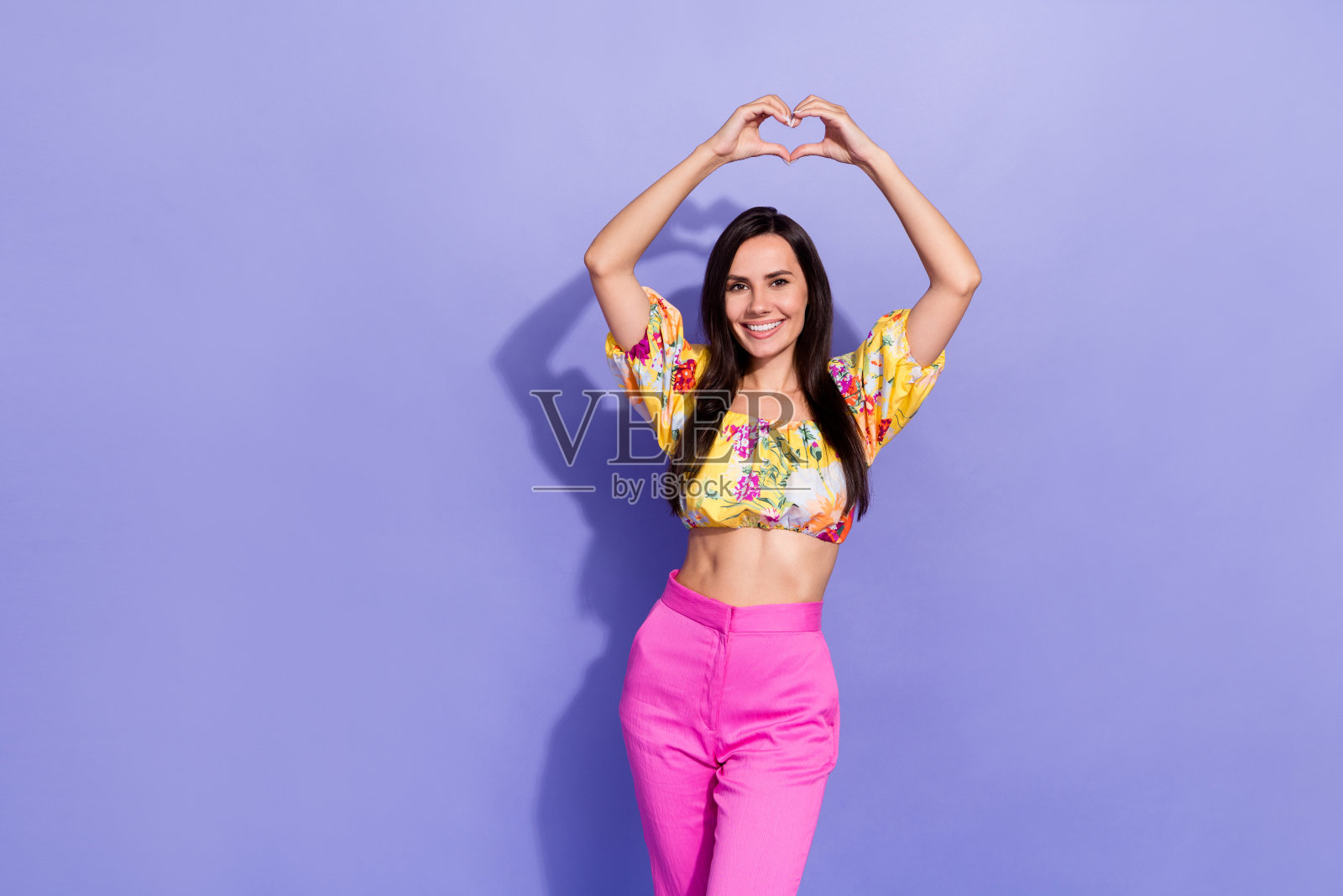 梦幻甜蜜的女孩穿着脱肩衬衫的照片,上升的手臂显示心空空间孤立的紫色背景照片摄影图片