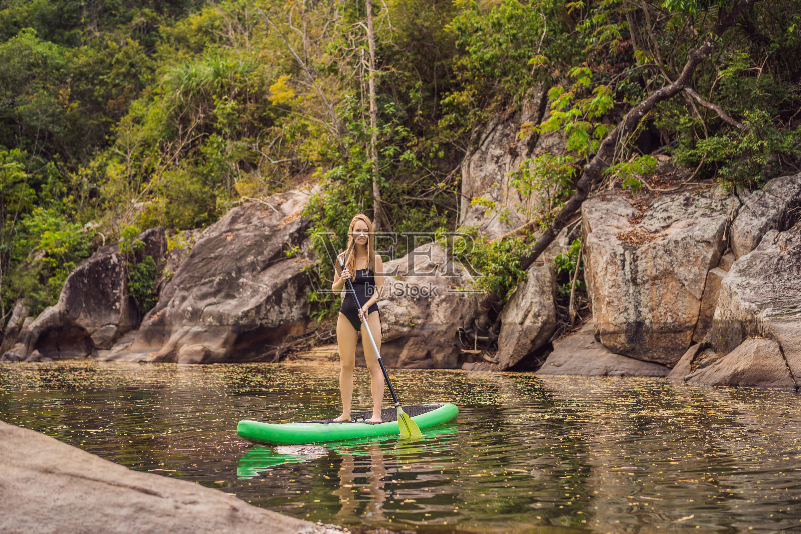 站起来桨板女人在湖上桨板站在桨板在蓝色的水快乐。年轻女子在桨板上的动作镜头照片摄影图片