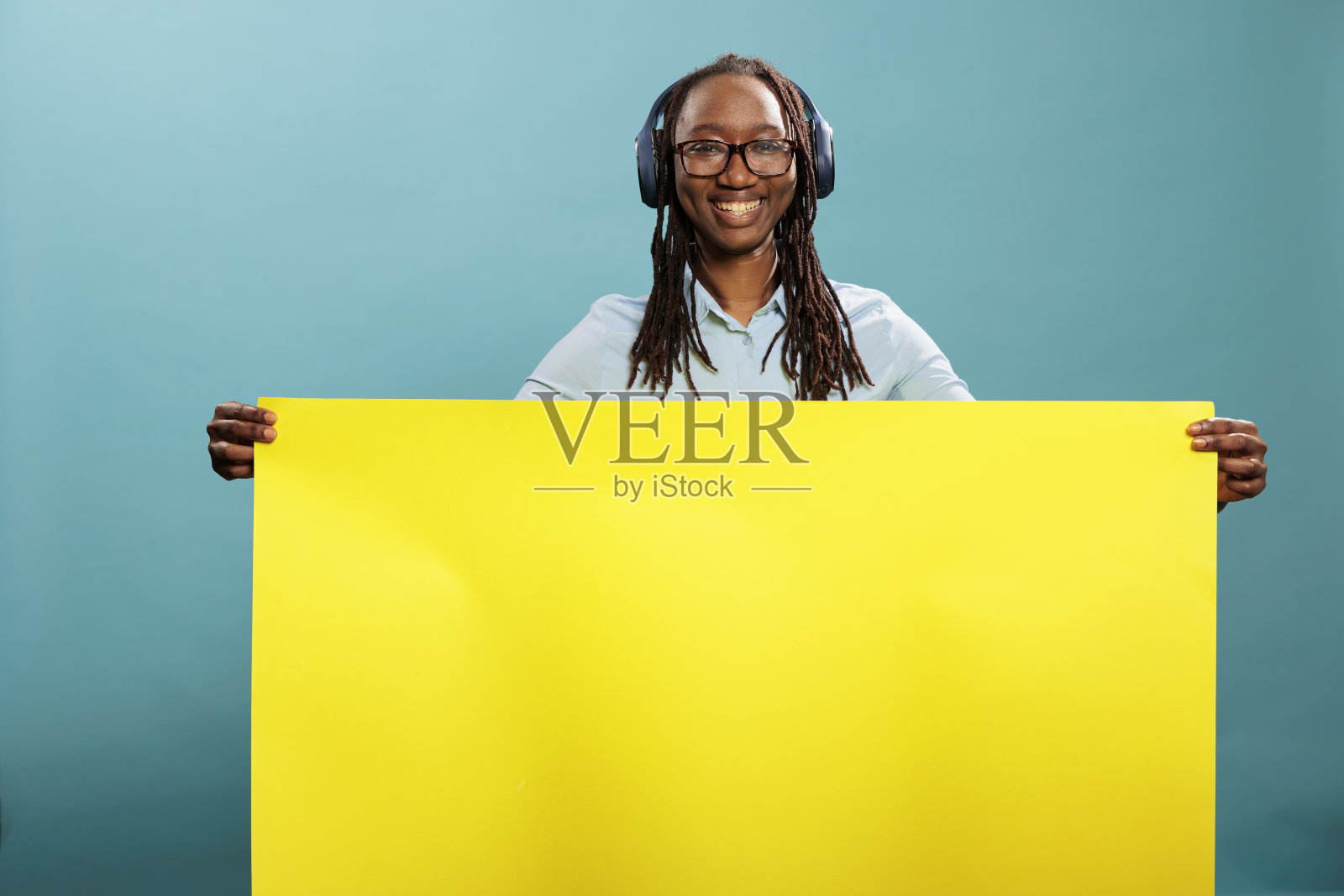 自信的年轻人,戴着电子耳机和空的广告海报照片摄影图片