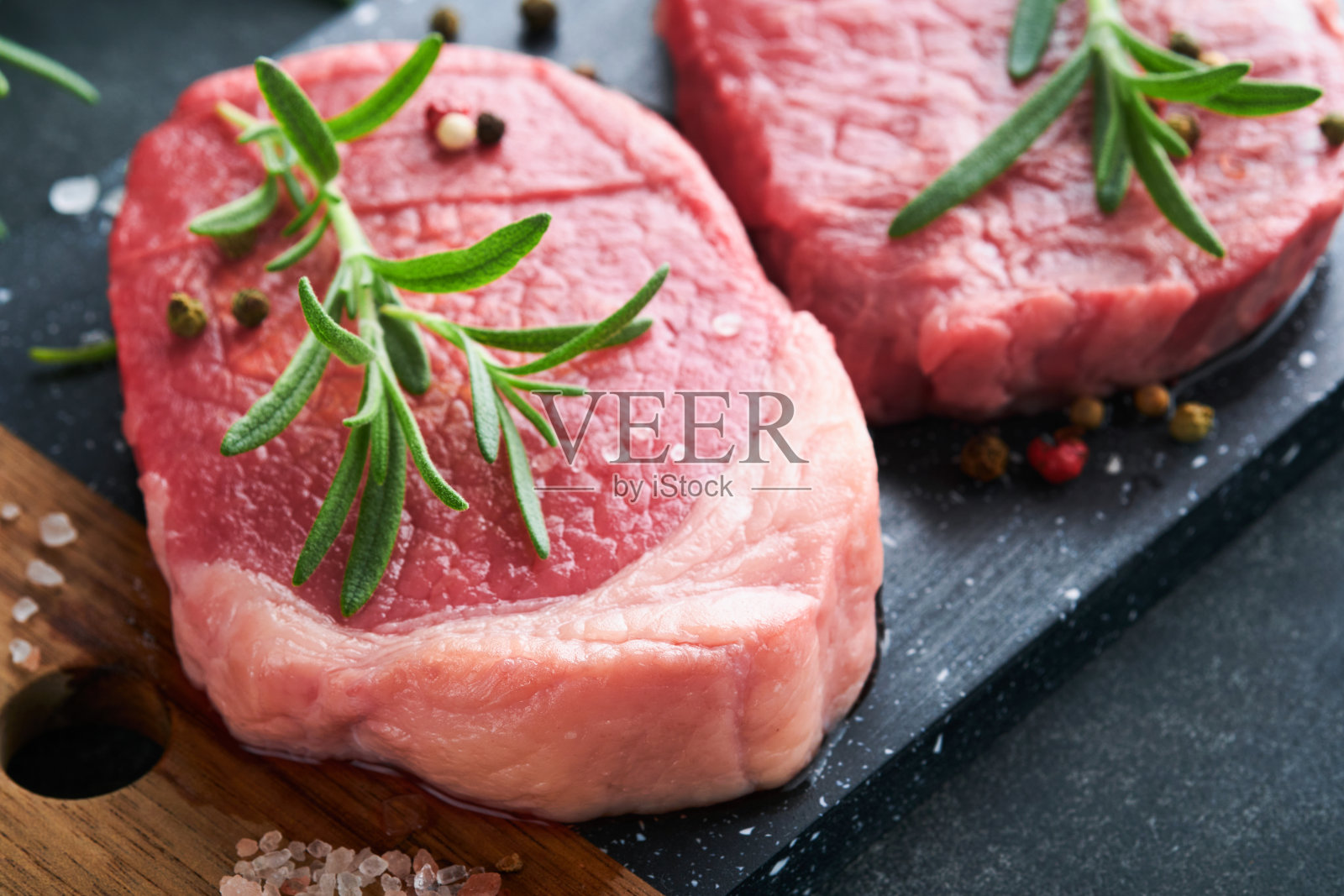 牛排。新鲜菲力牛排与香料迷迭香和胡椒在黑色大理石板灰色的背景。前视图。模拟。照片摄影图片