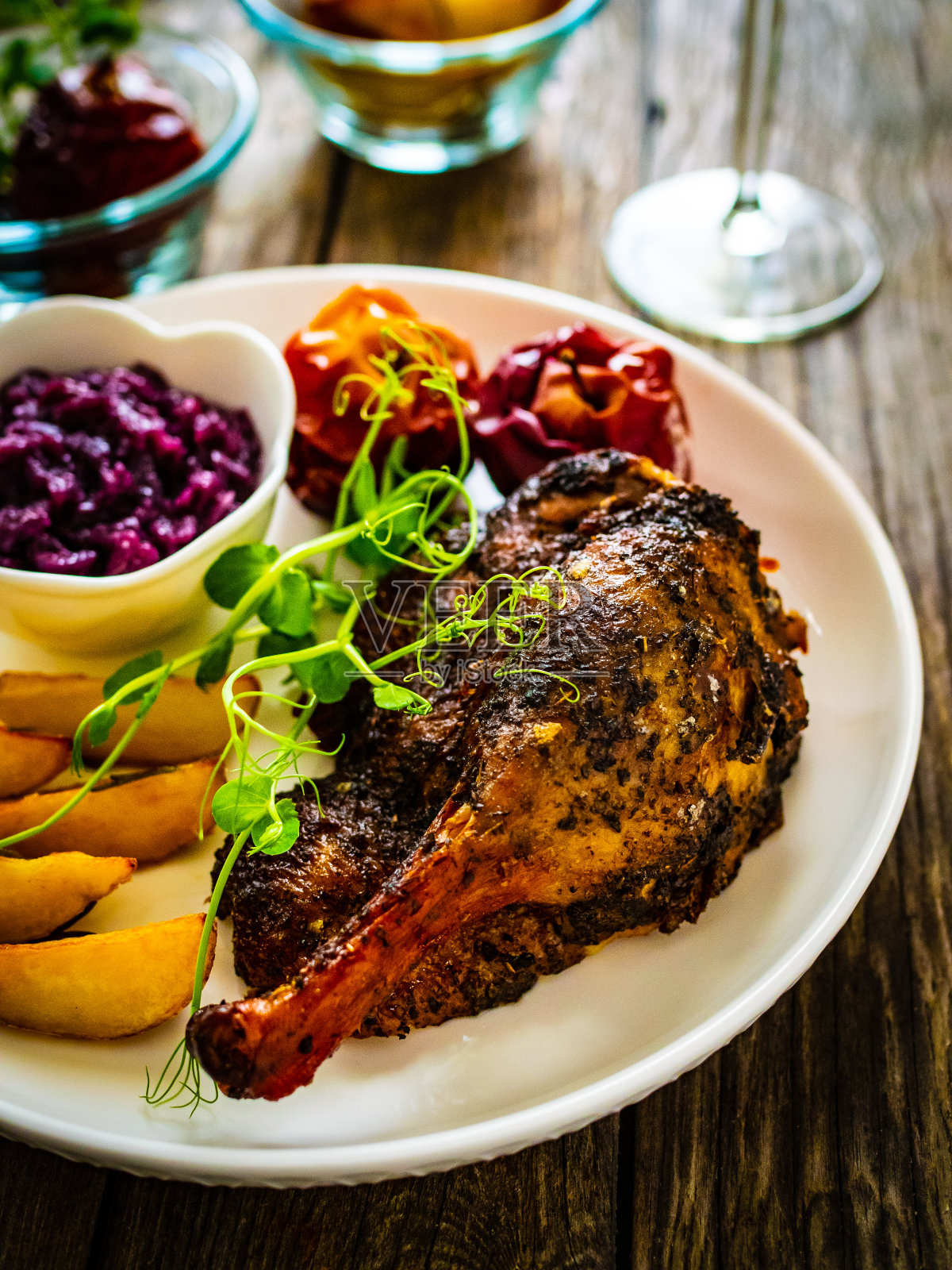 木桌上摆着烤鸭腿和蔬菜照片摄影图片