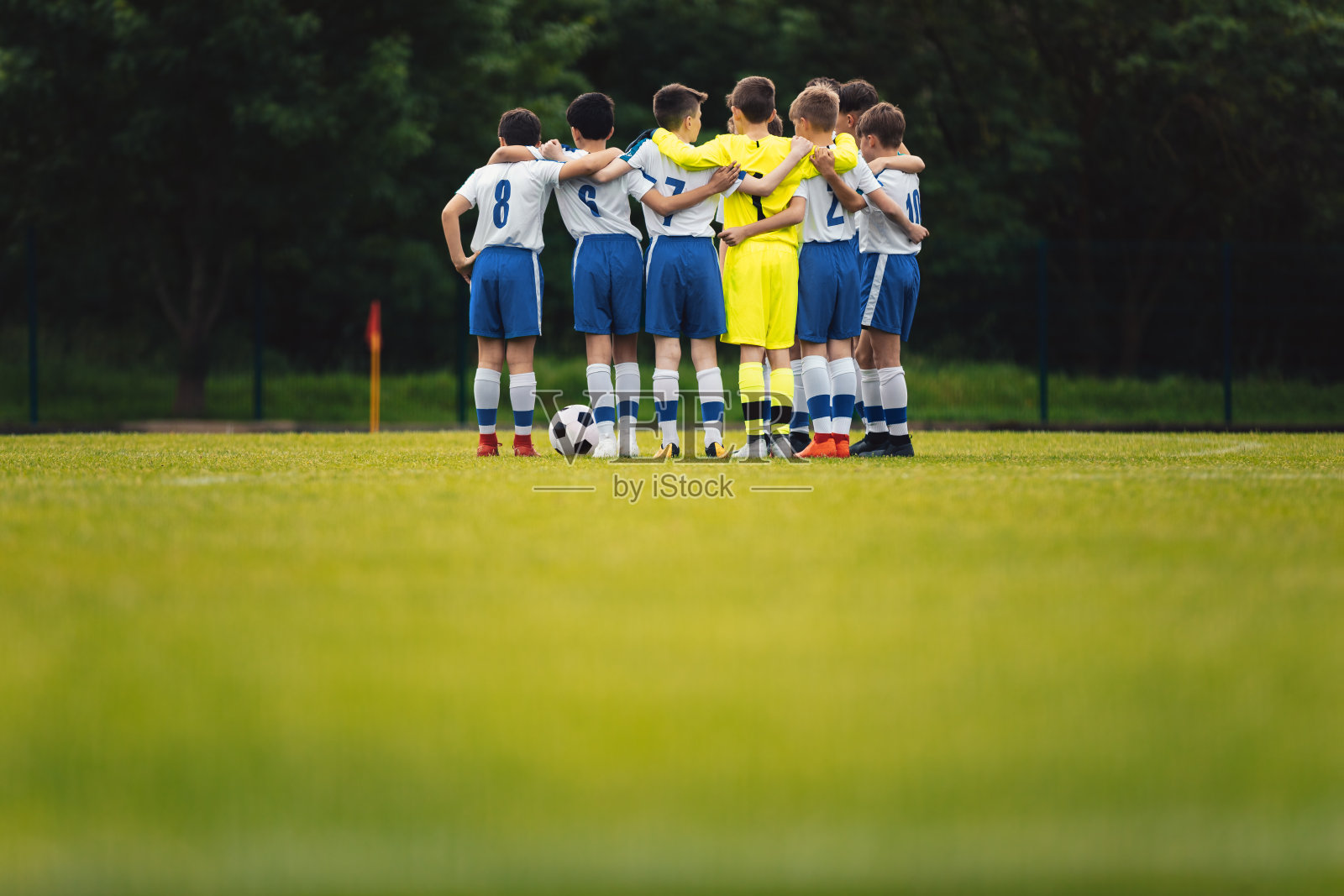 快乐的孩子们在做运动。青年队在圆圈内庆祝胜利。积极性很高的儿童运动队举起手来。学校足球照片摄影图片