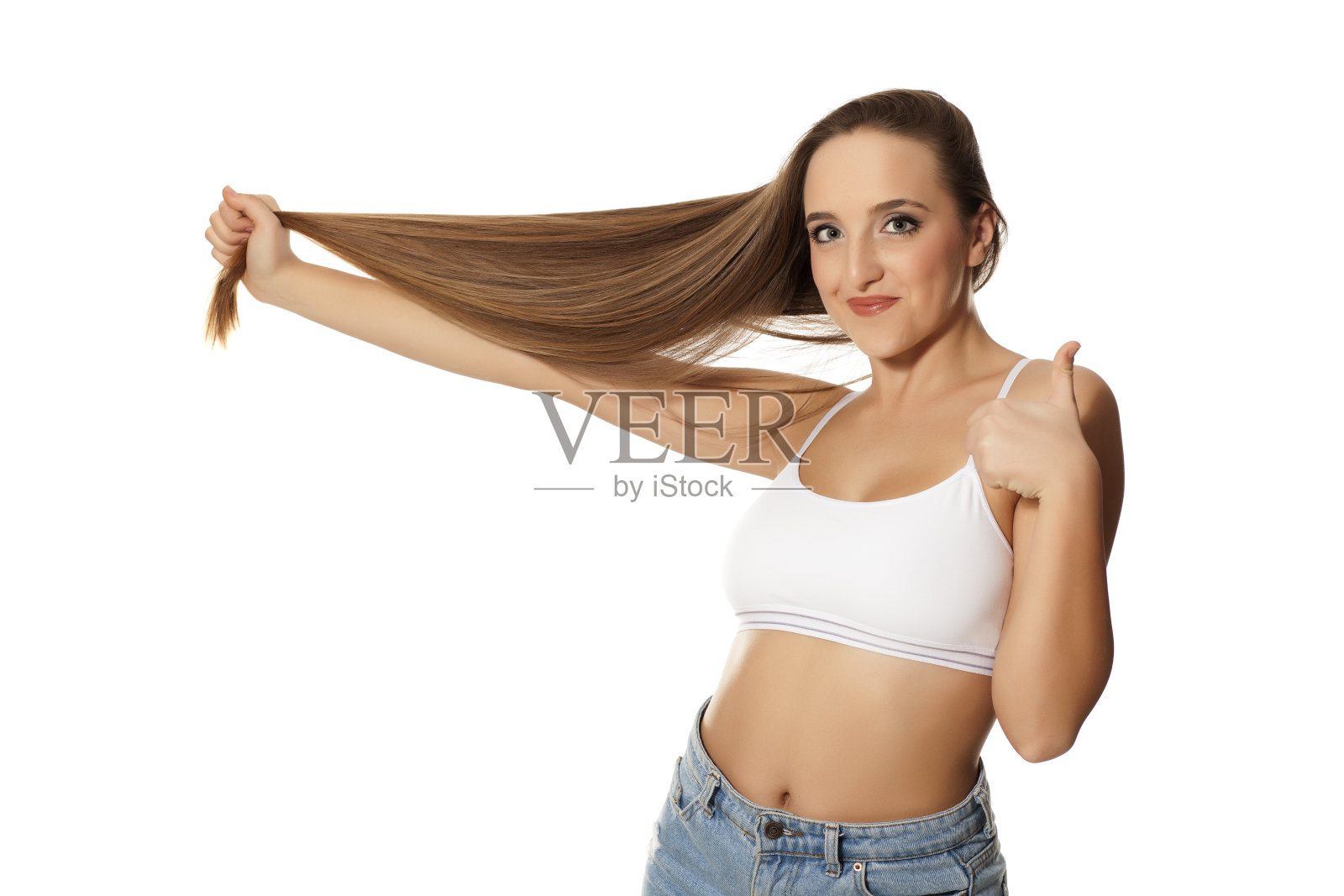 年轻女子握着她的长发,在白色背景上竖起大拇指照片摄影图片