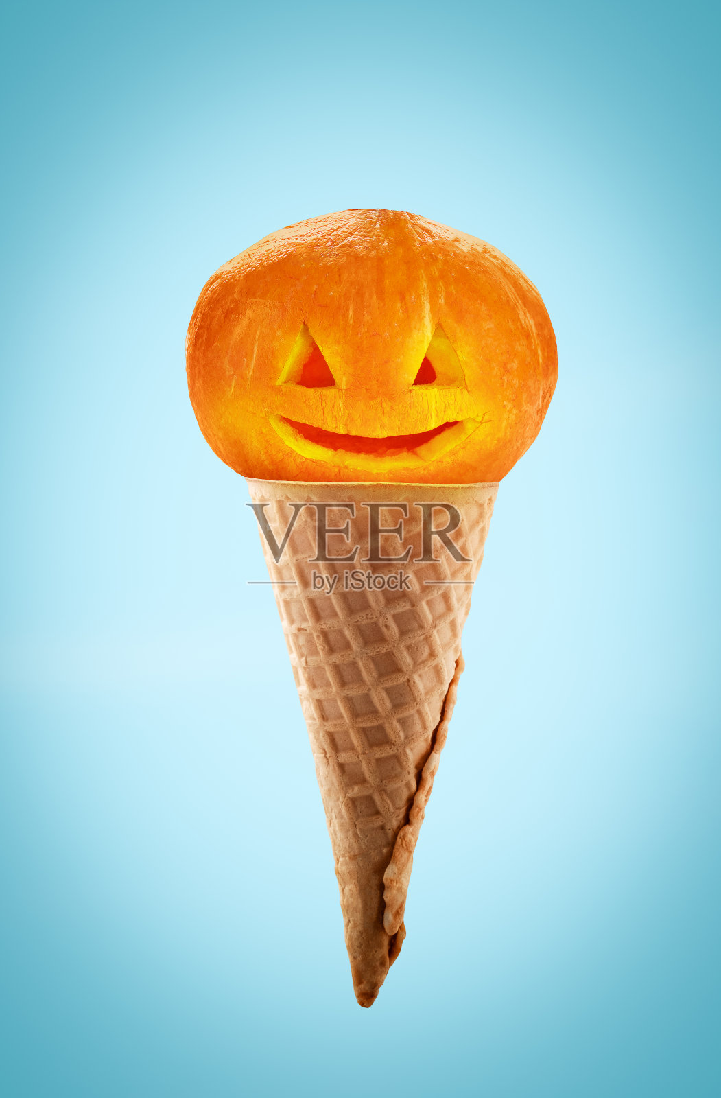 创意最小艺术万圣节海报。蓝色背景下华夫饼筒里可怕的南瓜。照片摄影图片