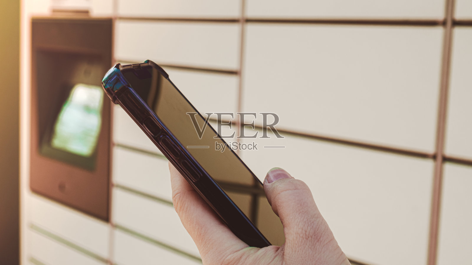 女性手拿手机,旁边的包裹柜从购物柜收集包裹。女性Skans二维码在手机上自助寄存柜单元与条码阅读器现代运输和递送非接触式自动化邮筒照片摄影图片